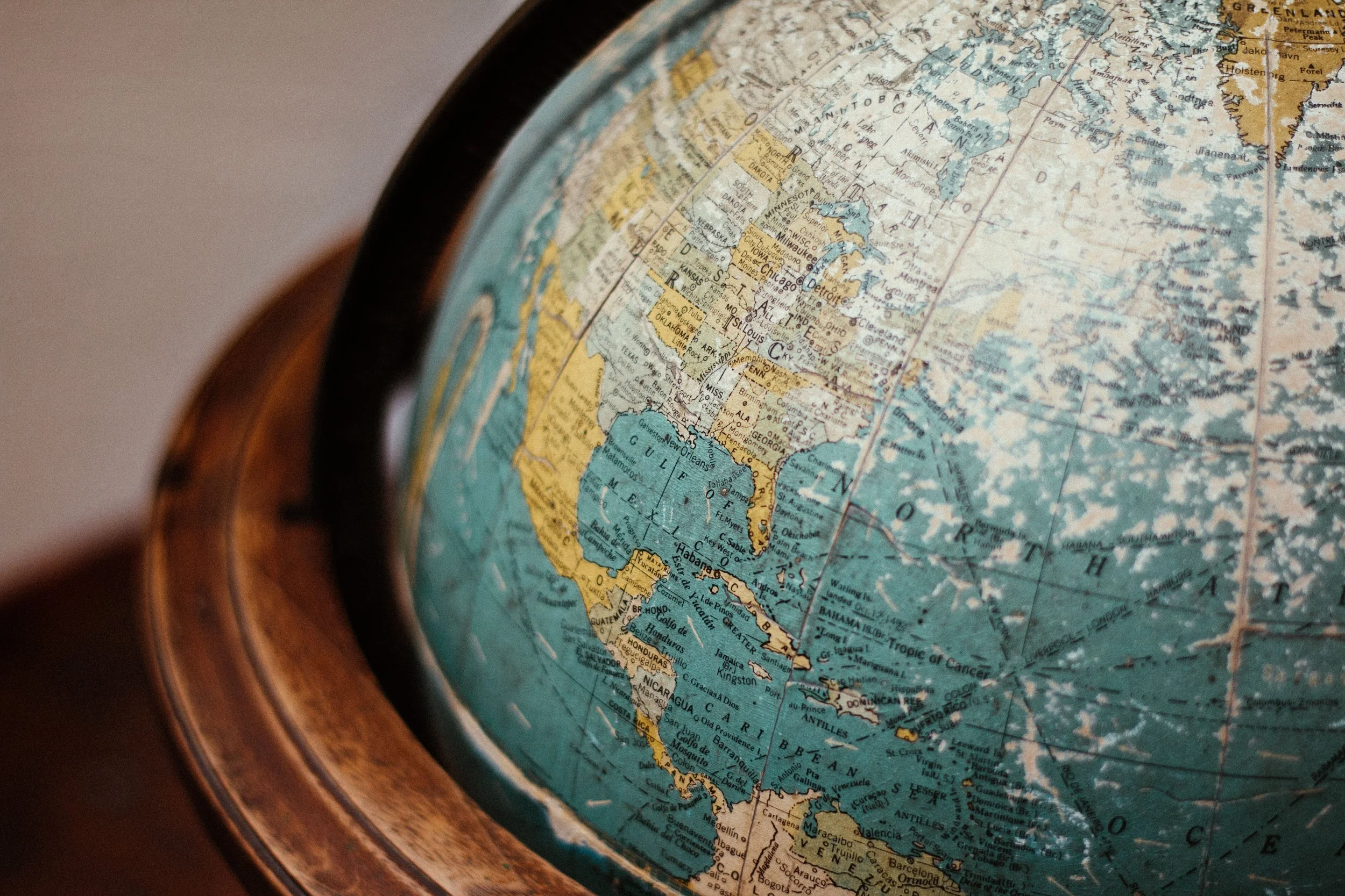 Close-up of a globe showing North, Central, and South America with countries like the United States, Canada, Mexico, Brazil, and Argentina, featuring detailed geographical and political maps, mounted on a wooden stand.