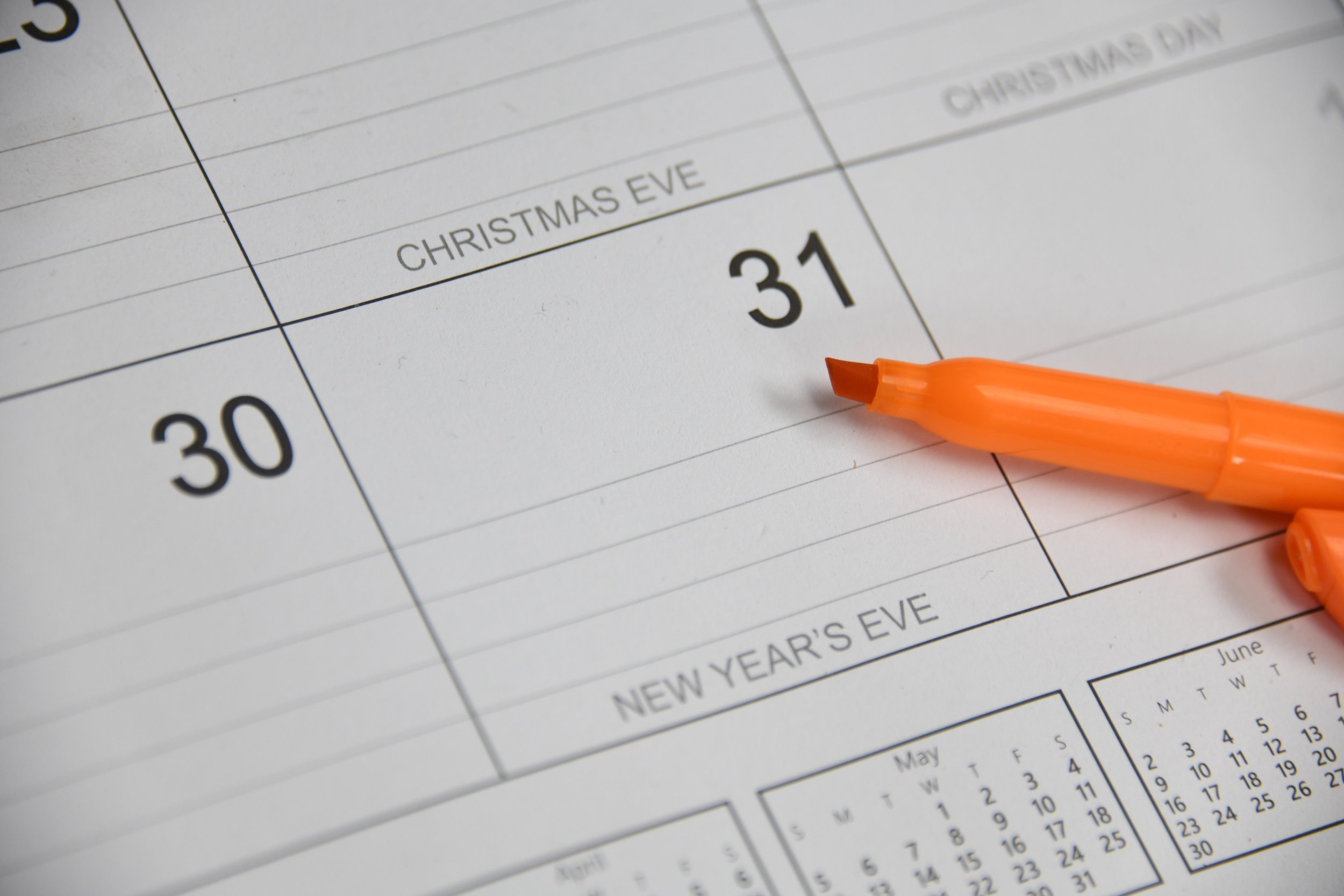 Close-up of a calendar page highlighting December 31st, with an orange marker nearby, indicating New Year's Eve.