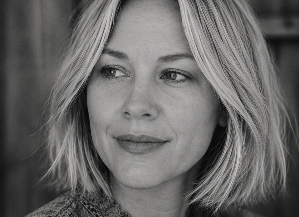 Close-up black and white portrait of a woman with shoulder-length blonde hair, looking to her right with a thoughtful expression.