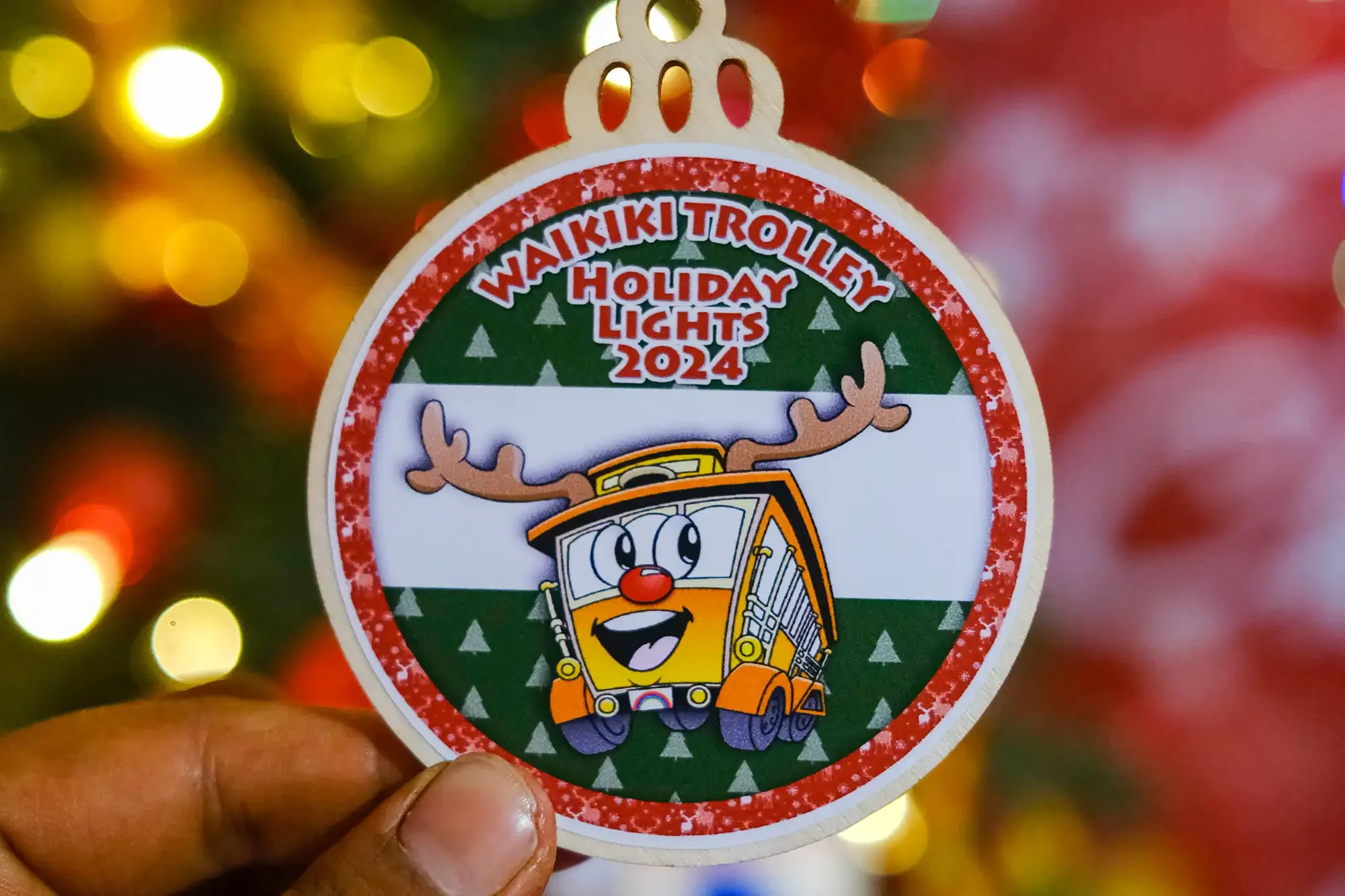 A circular ornament featuring Winnie the Pooh and a character in a Wanikiki Trolley with reindeer antlers, promoting the 2024 holiday lights event.