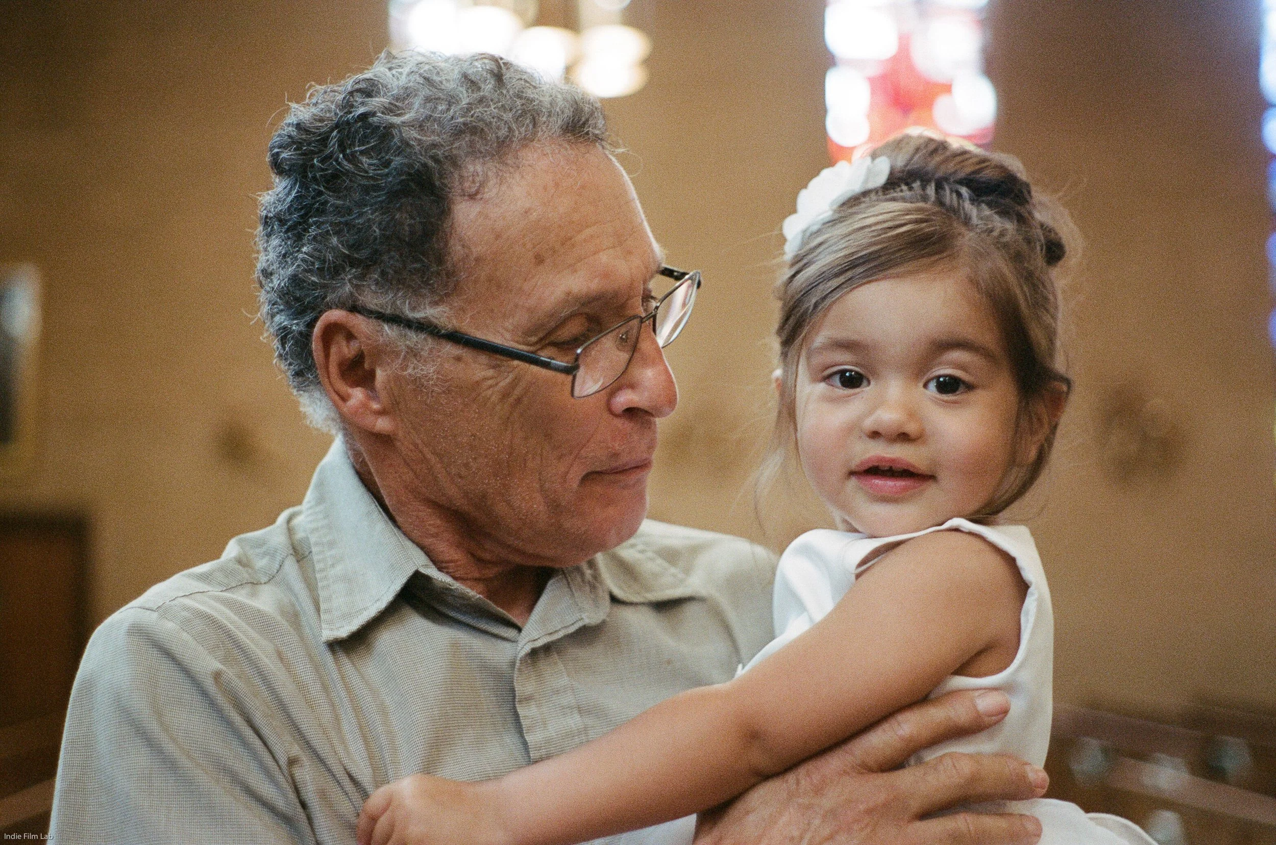 An elderly man holding a young girl in a church or chapel