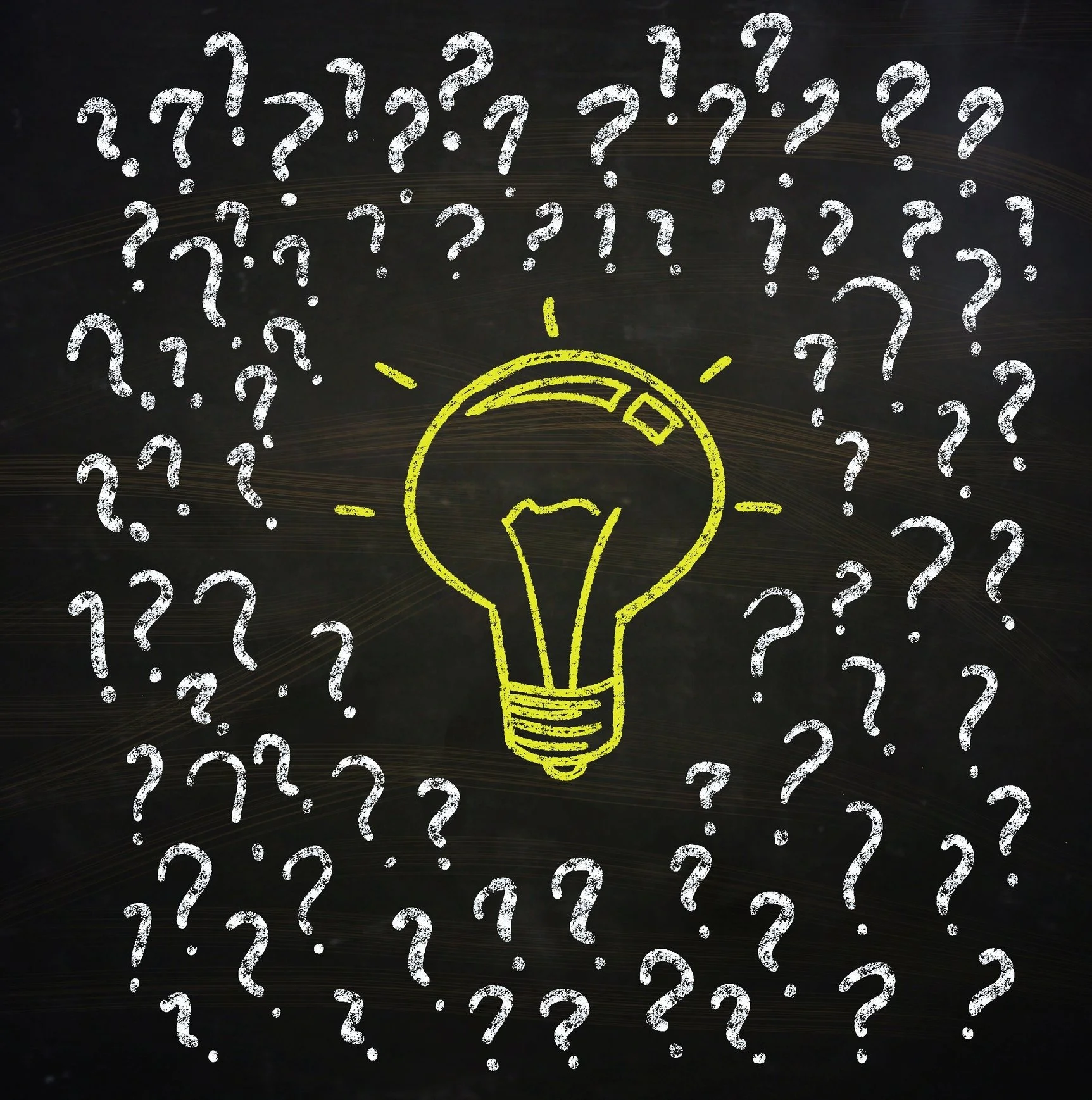 A blackboard with a yellow chalk illustration of a lightbulb in the center, surrounded by numerous white chalk question marks.