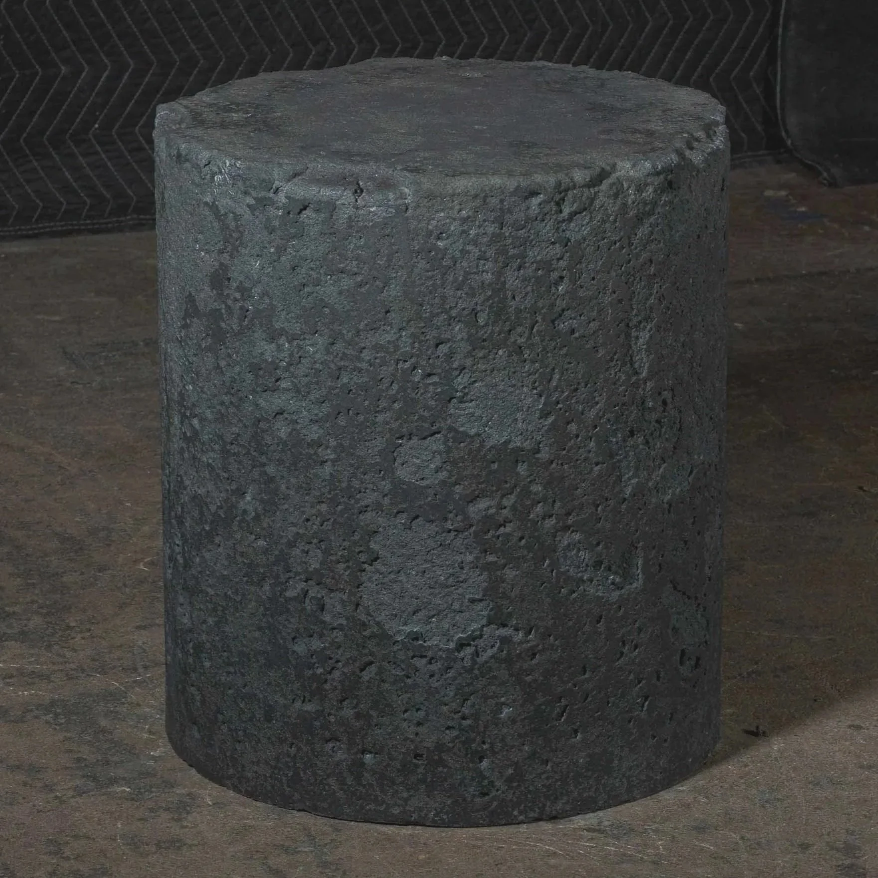 Sculptural concrete pedestal side table with rough tactile surface, monolithic form, and atmospheric industrial character.