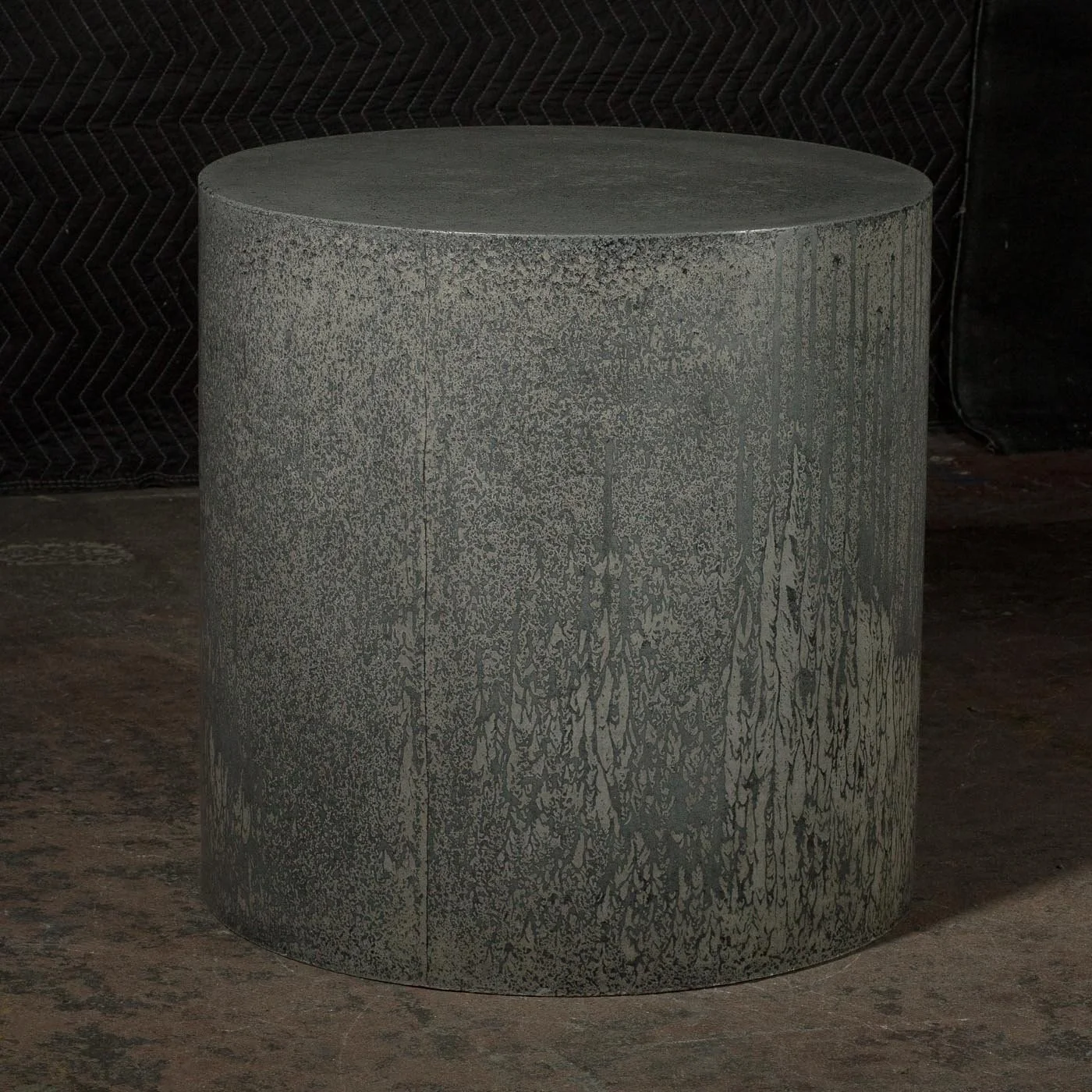 Architectural concrete cylinder featuring layered grey mineral variation and subtle flowing surface conditions within a reduced cylindrical form.