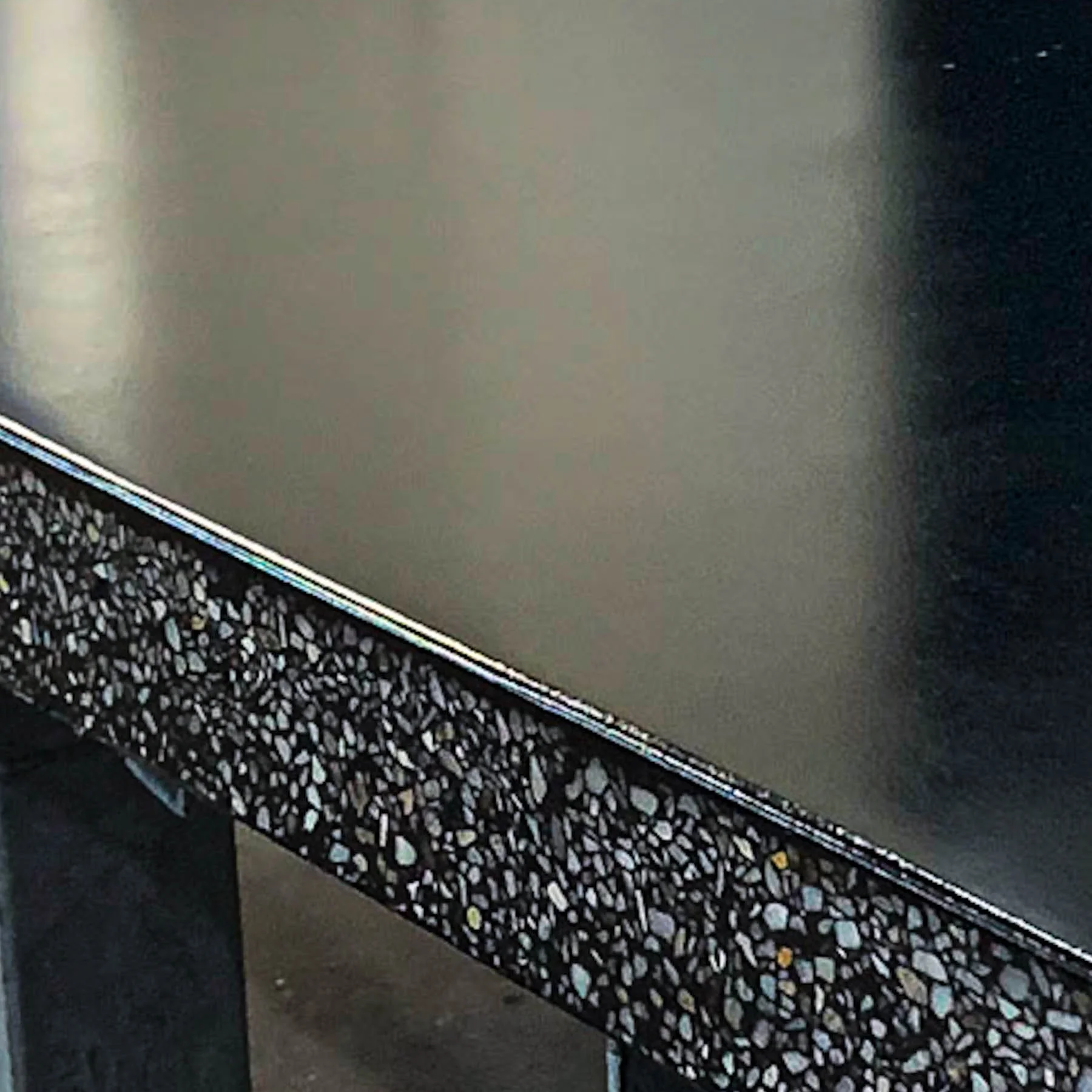 Close-up detail of hand-finished black terrazzo concrete with exposed aggregate by The Concrete Anomaly.