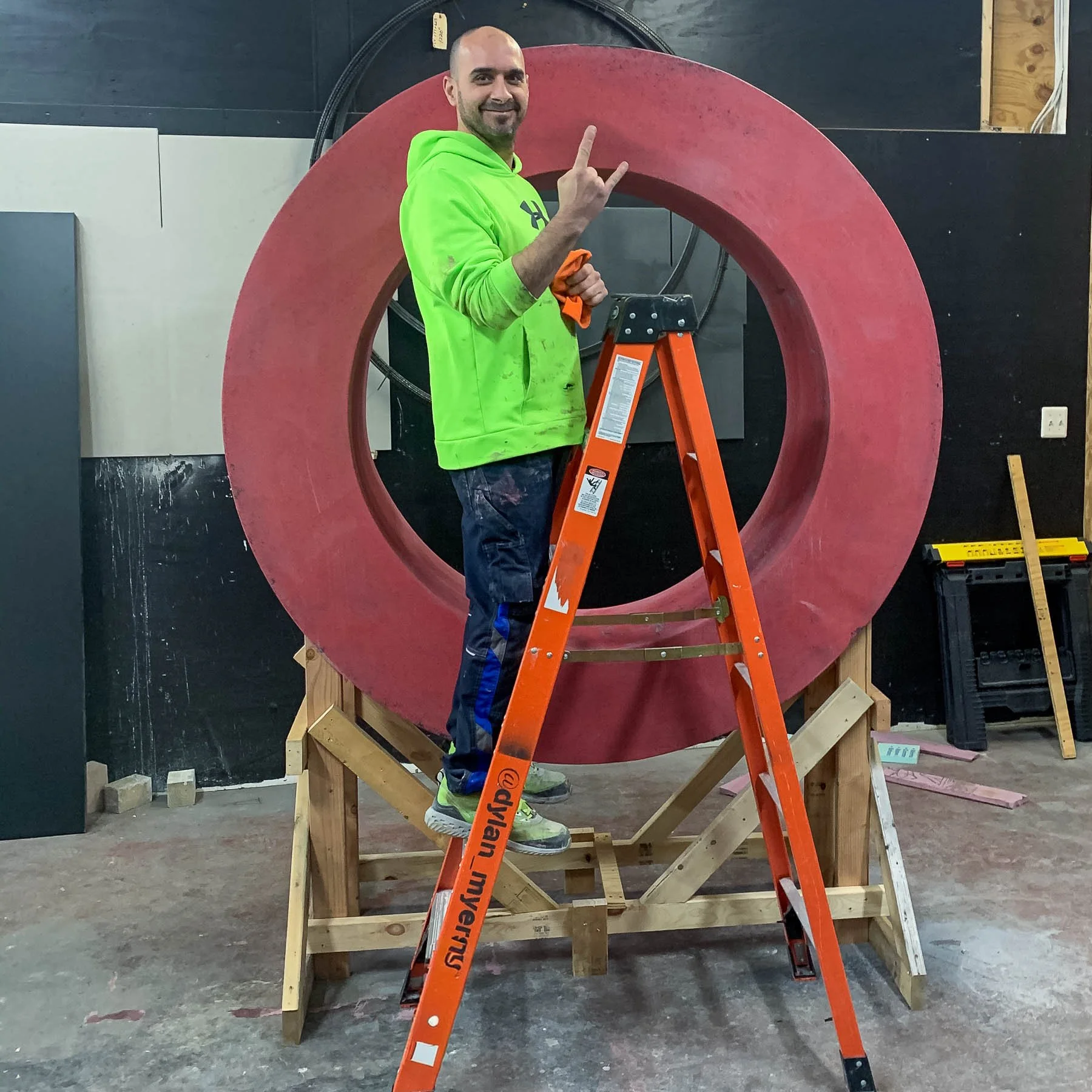 Dylan Myers standing beside the red concrete letter O during fabrication of the monumental LOVE sculpture.