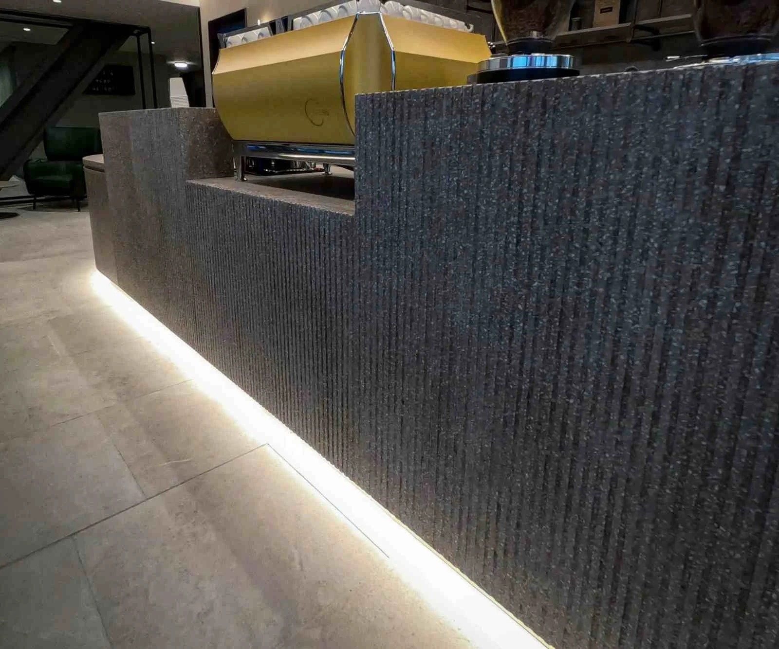 Custom cast concrete reception desk with exposed aggregate finish and integrated LED base lighting in a contemporary interior.