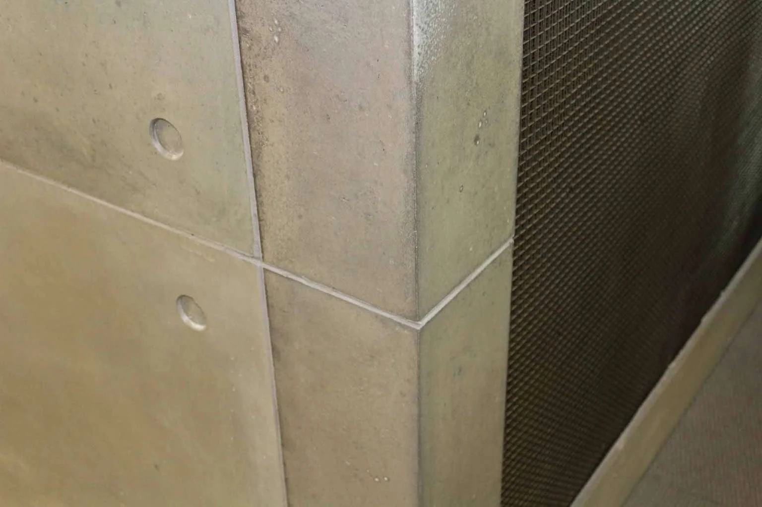 Close-up detail of architectural concrete wall panel joints and integrated ventilation, fabricated by The Concrete Anomaly for a commercial interior.