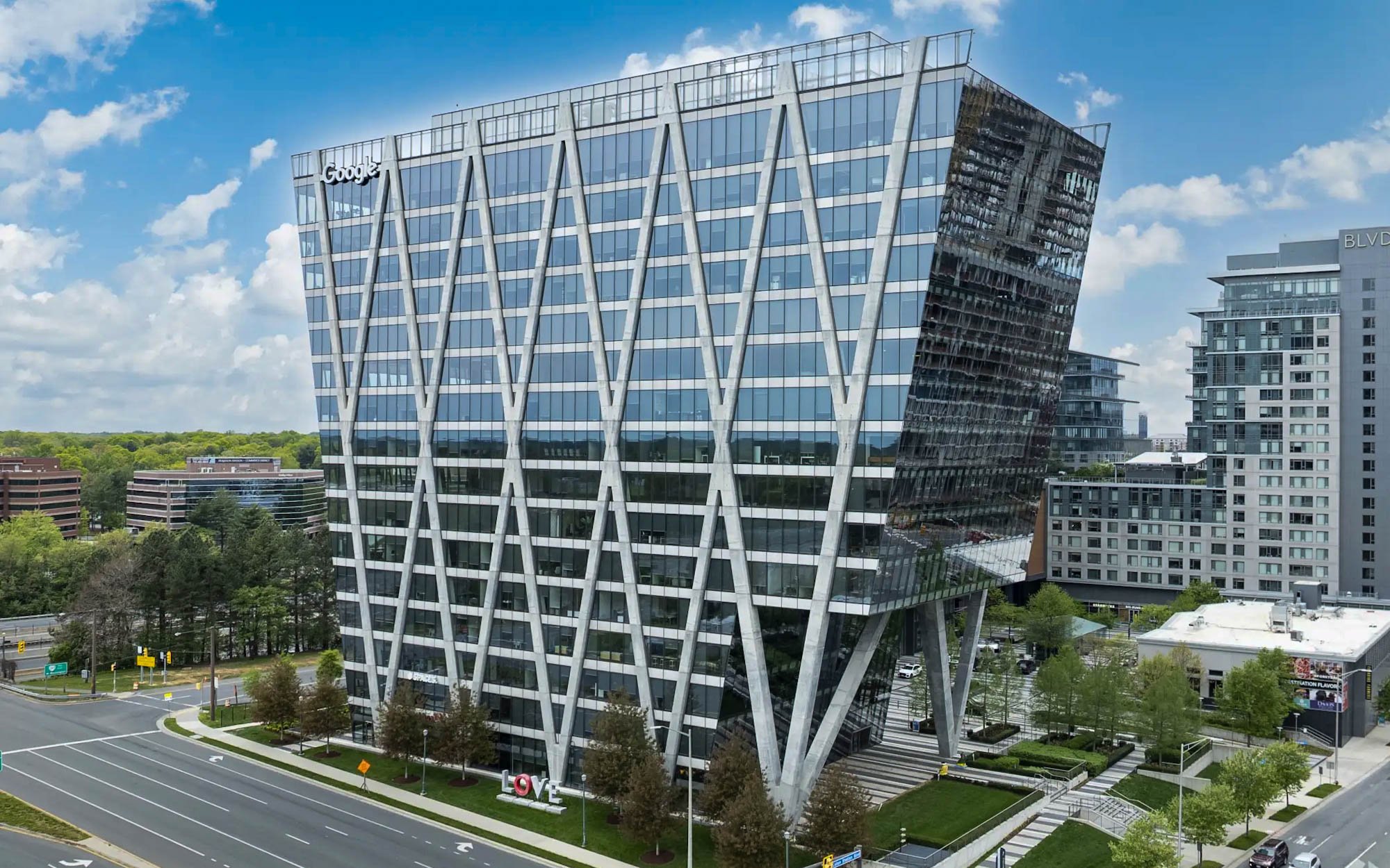 Aerial view of JAHN-designed 1900 Reston Metro Plaza at Reston Station with Dylan Myers’ Then LOVE Emerges concrete sculpture on the landscaped grounds behind the tower.