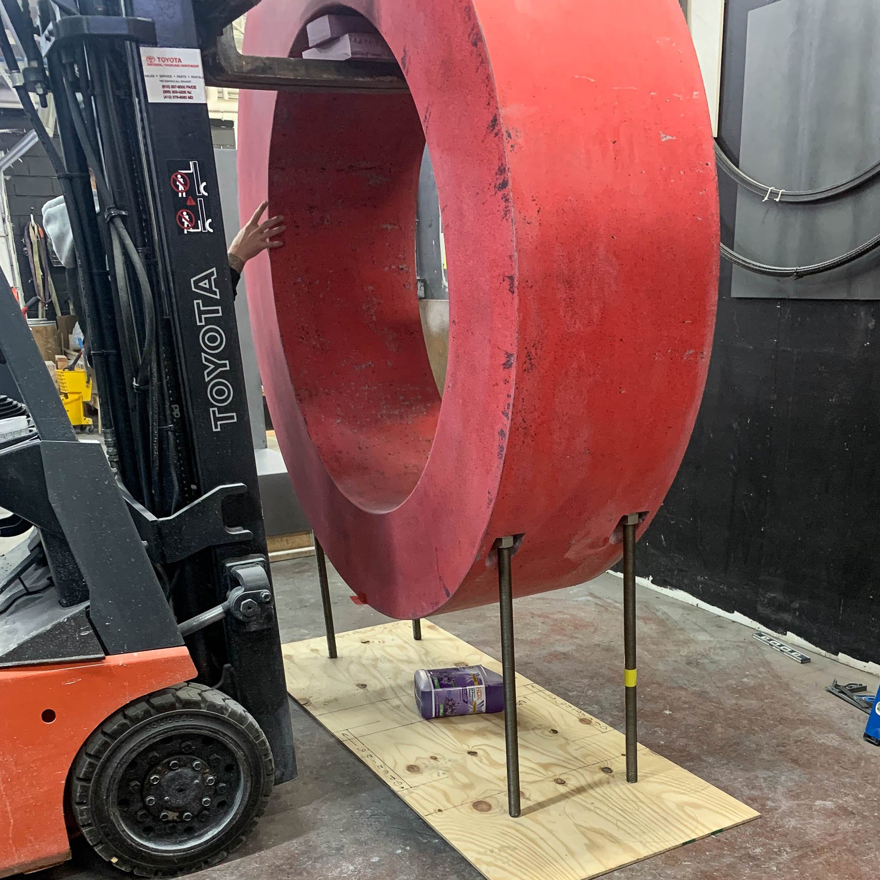 The red concrete letter O being positioned by forklift during studio assembly of the monumental LOVE sculpture.