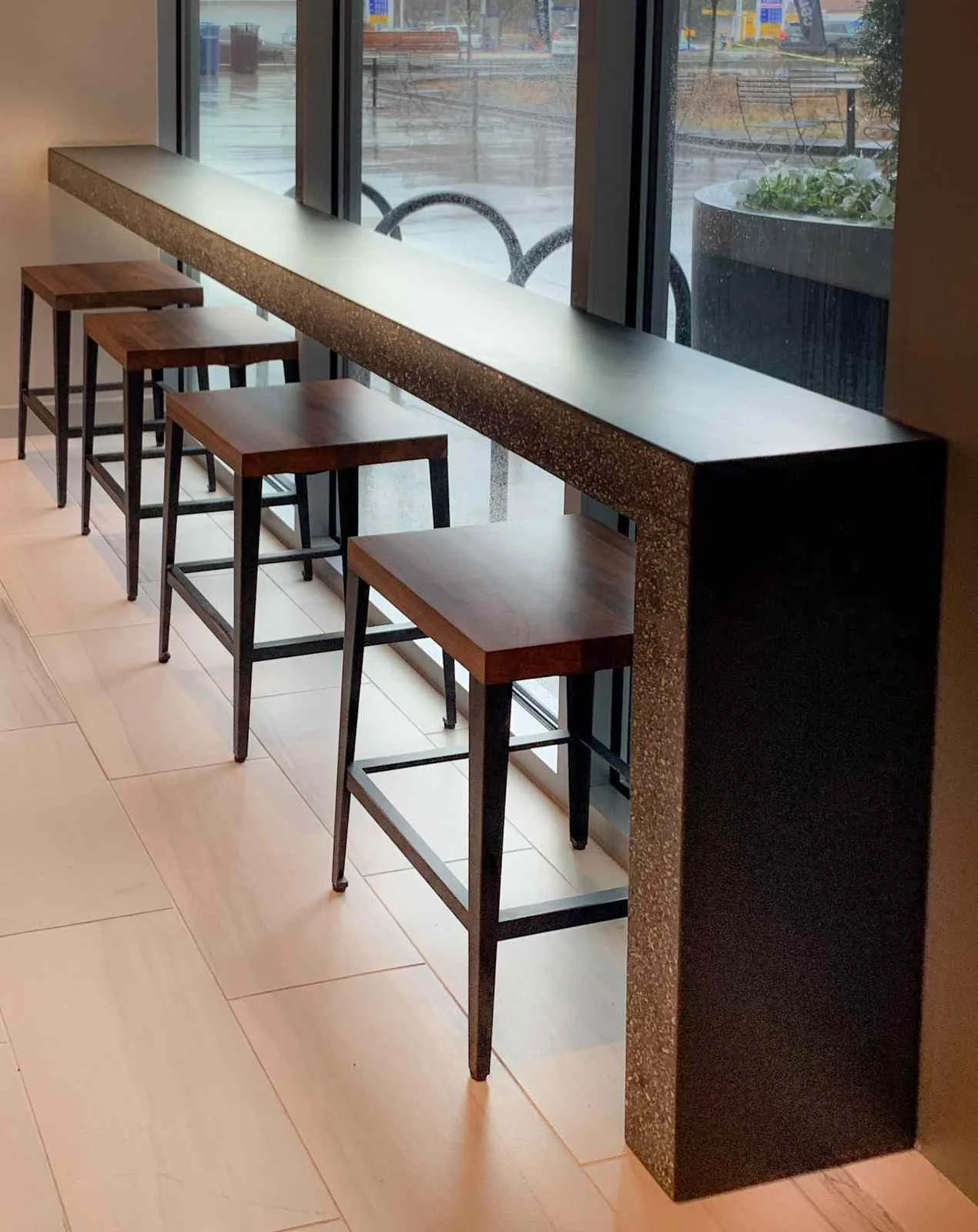 Custom concrete bar counter with monolithic edge, designed and fabricated by The Concrete Anomaly, installed along a window wall in a commercial interior.