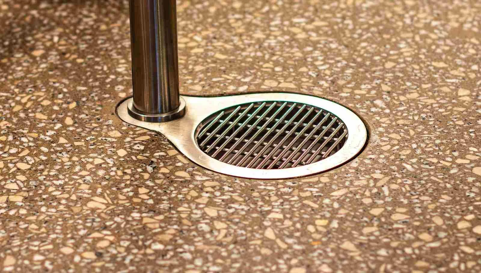 Close-up of a cast concrete floor surface with exposed aggregate and integrated floor drain detail.