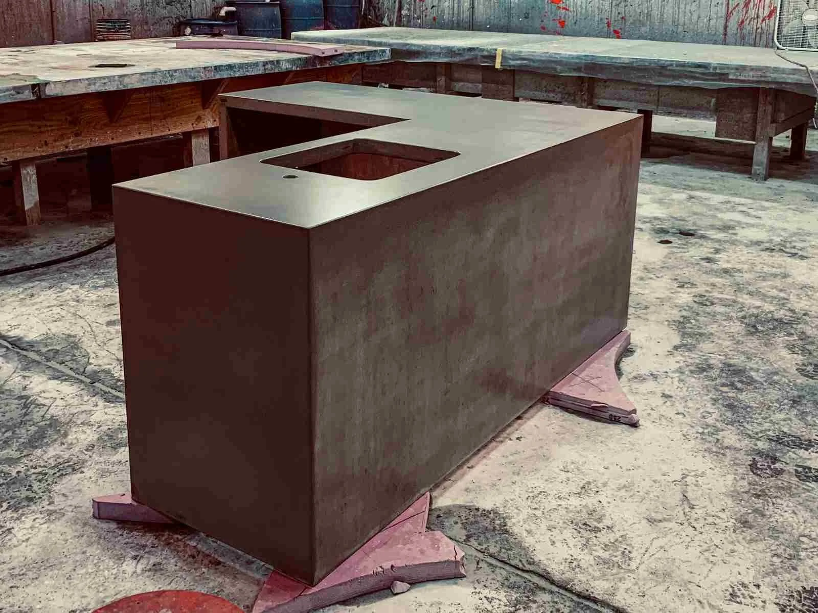 Custom cast concrete kitchen island in fabrication, shown with sink cutouts prior to finishing.