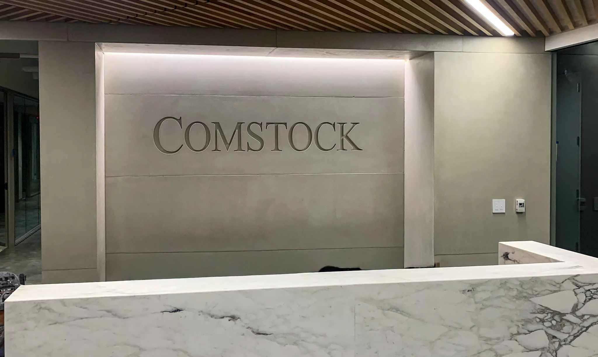 Custom cast concrete wall panels with integrated recessed lettering, forming a refined reception backdrop.