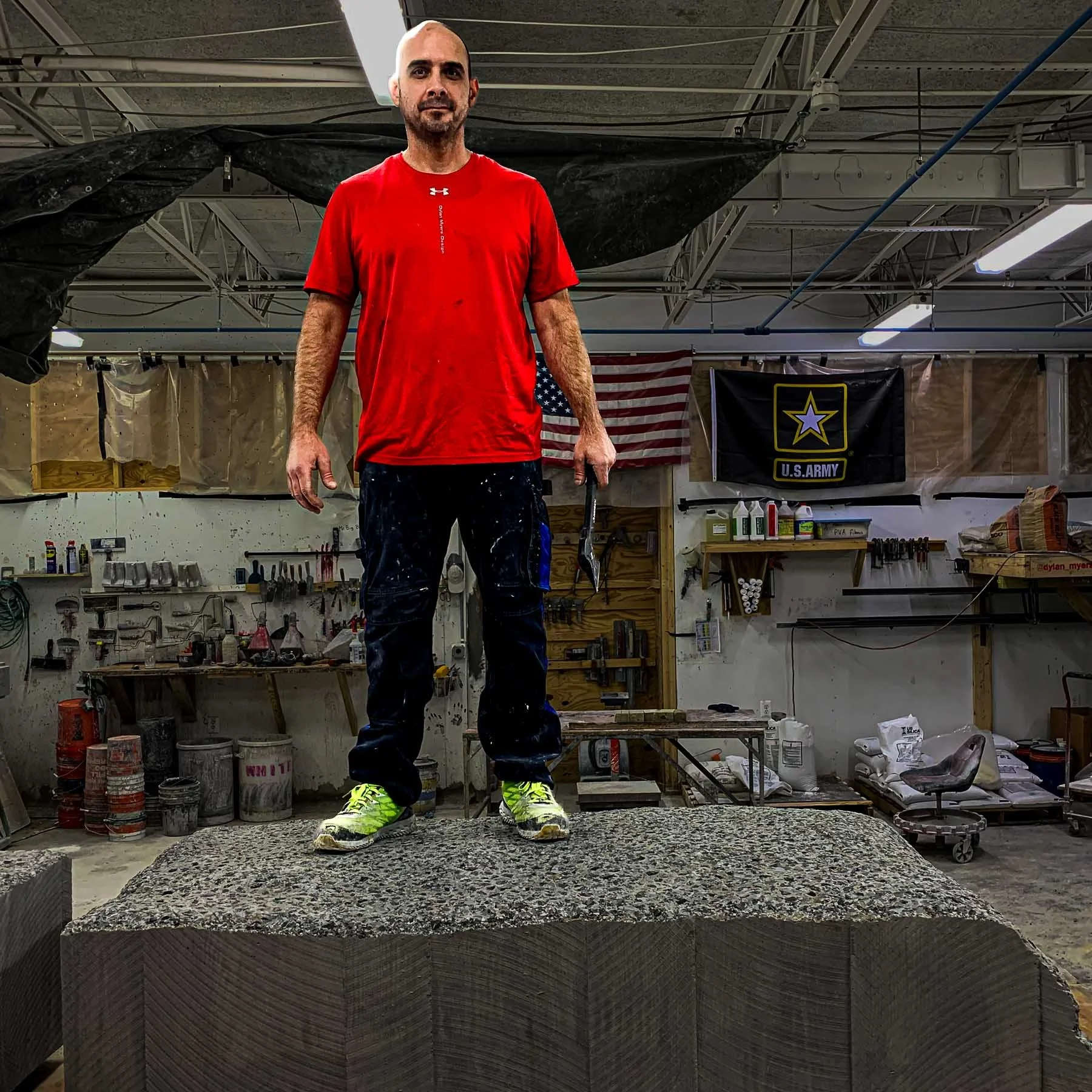 Dylan Myers standing on a monumental concrete LOVE sculpture component during studio fabrication.