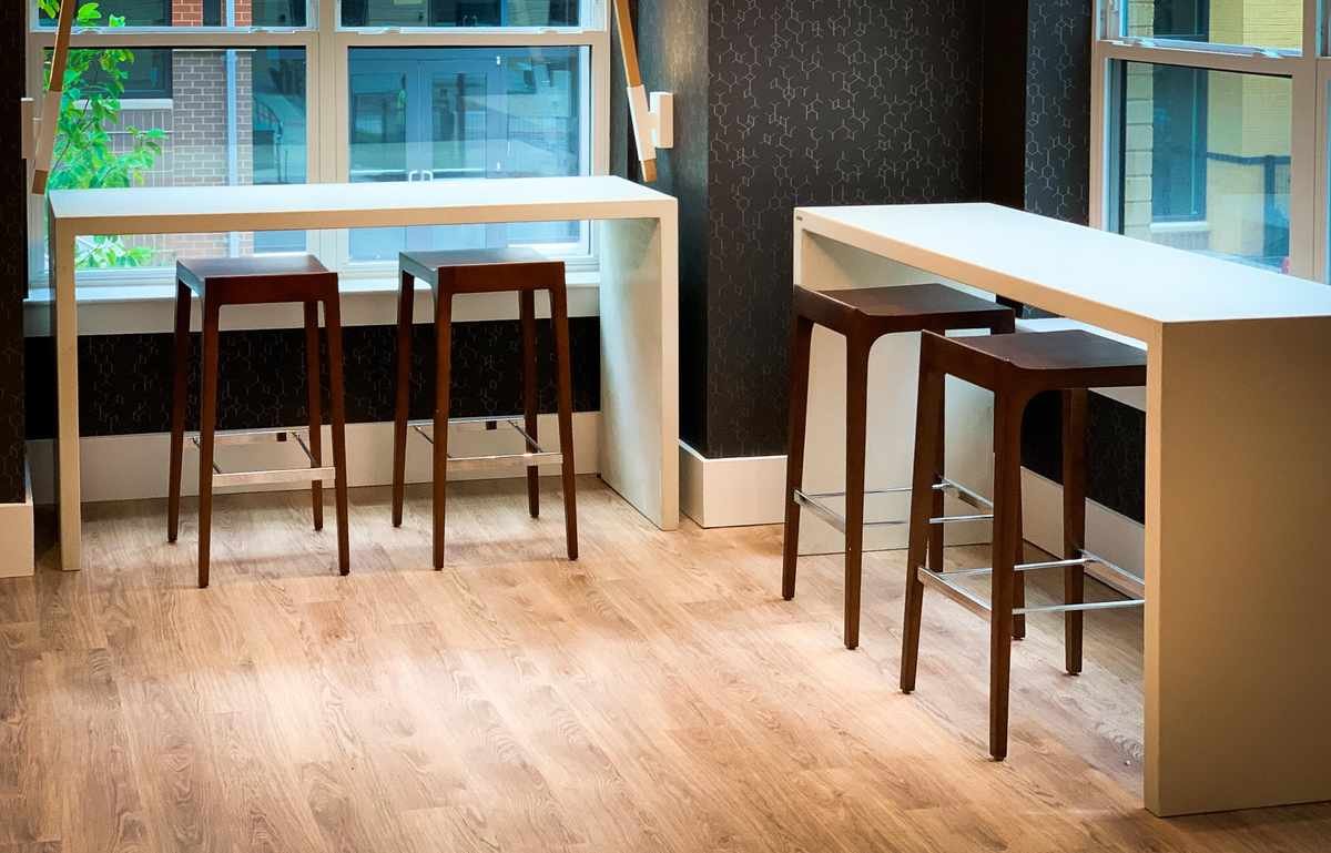 Custom cast concrete bar-height tables positioned along window wall in a modern commercial interior.