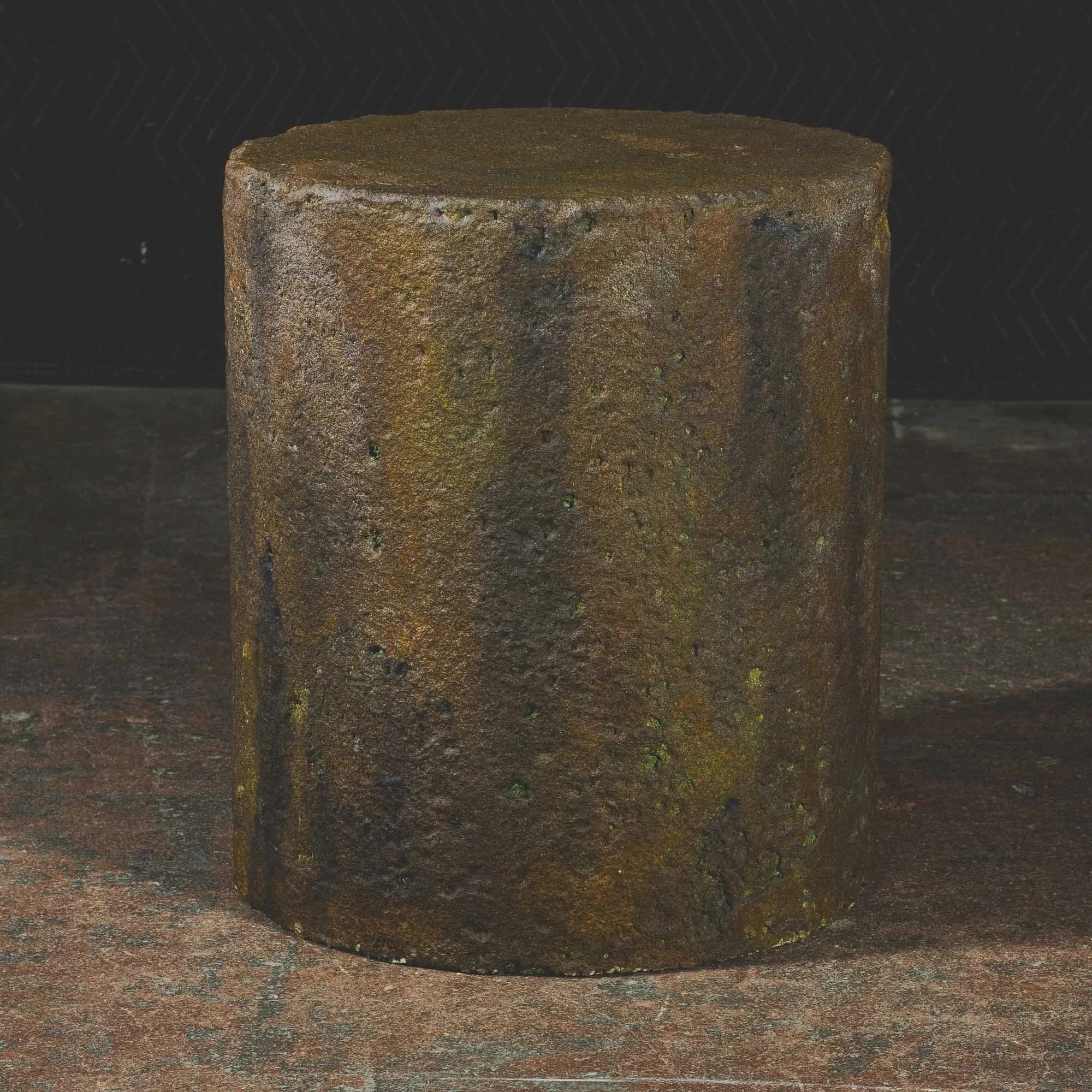Sculptural concrete pedestal with deep oxidized patina and eroded metallic surface character inspired by aged steel and elemental decay.
