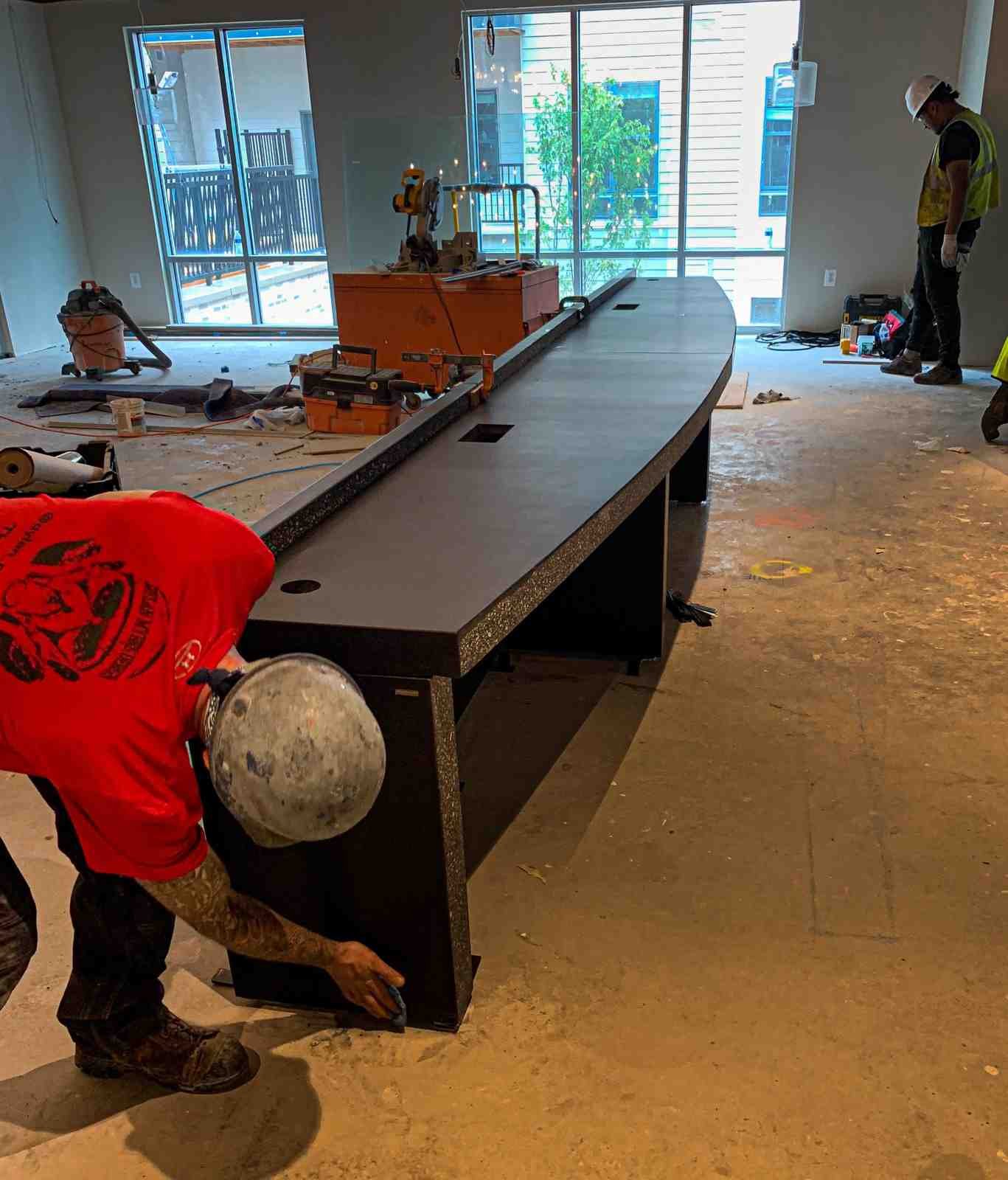 On-site installation of a custom turnkey concrete desk, showing handling and placement of the monolithic desk element by The Concrete Anomaly.