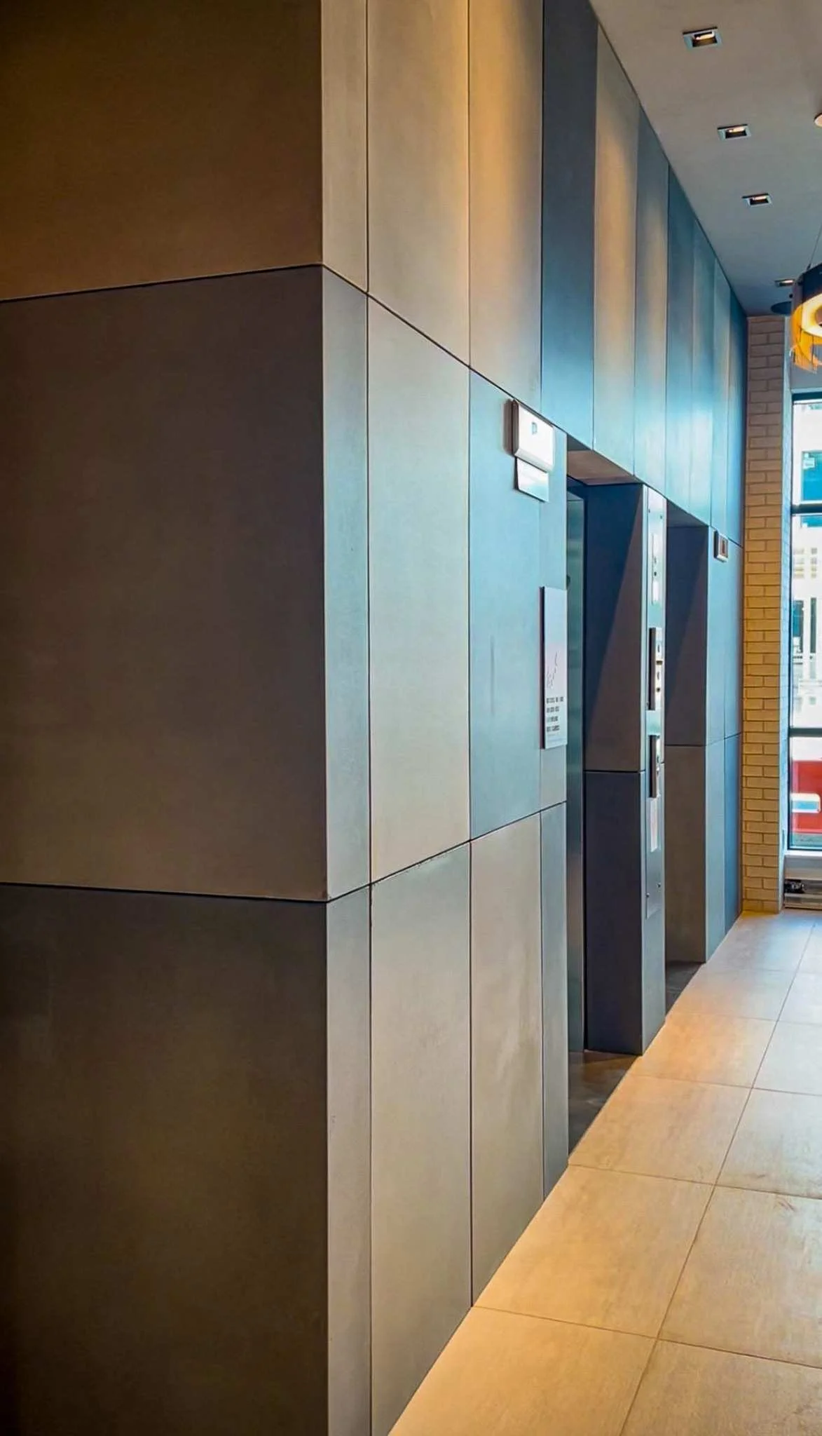 Precast concrete wall and corner wrap system with aligned panel joints along elevator corridor.