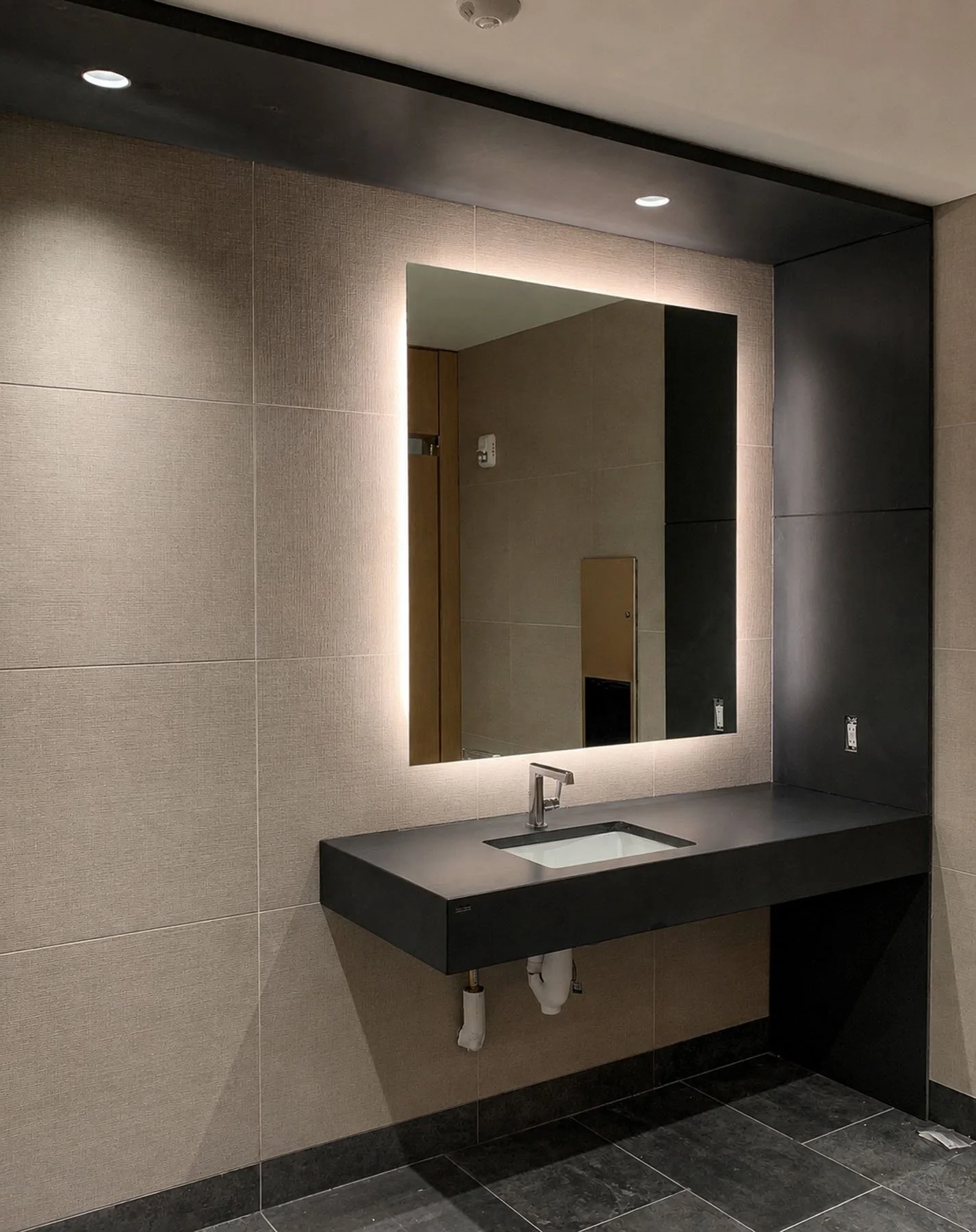 Custom black concrete sink and integrated vanity by The Concrete Anomaly installed within a contemporary luxury bathroom.