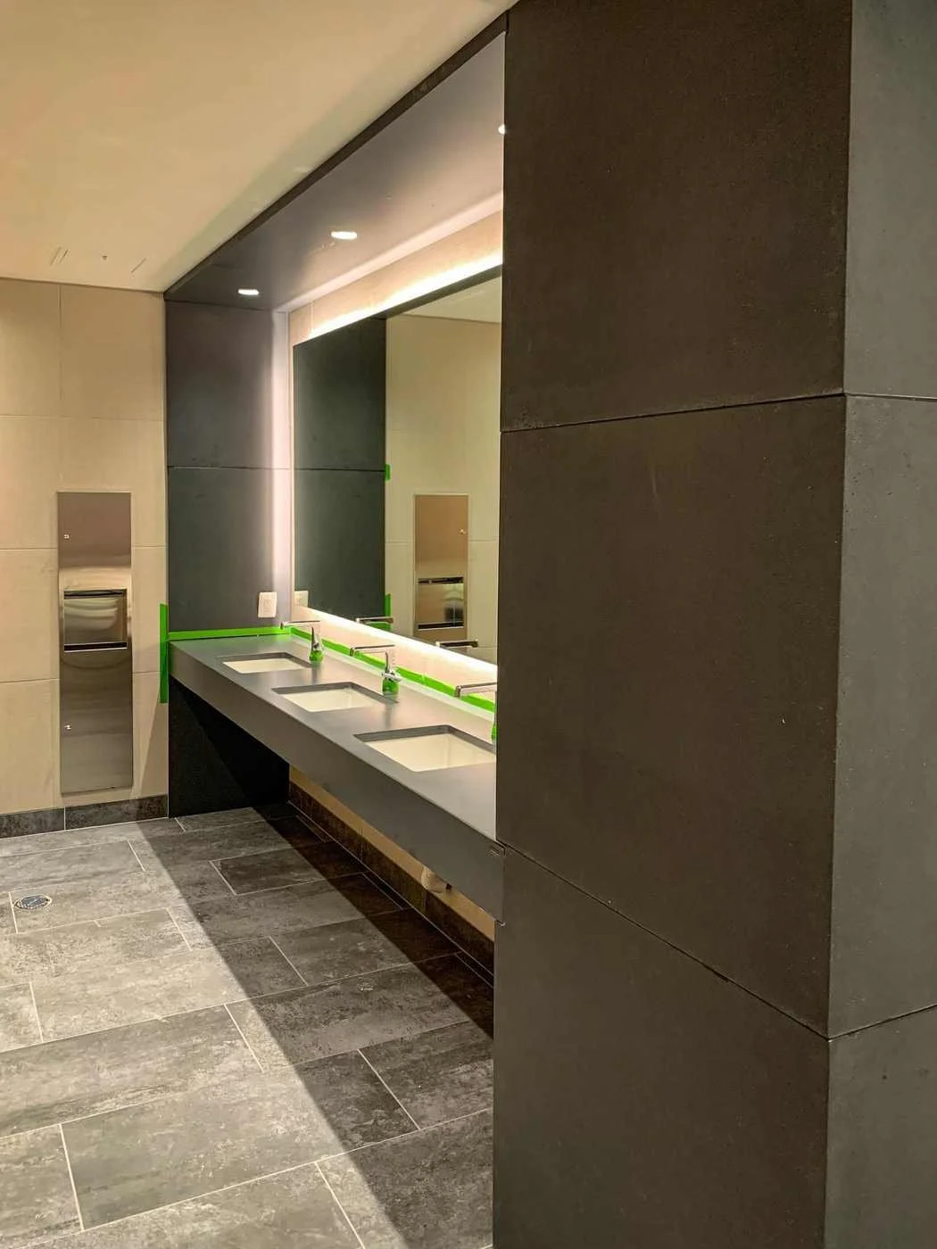 Custom cast concrete restroom vanity with multiple integrated sinks and continuous countertop surface in a public restroom.