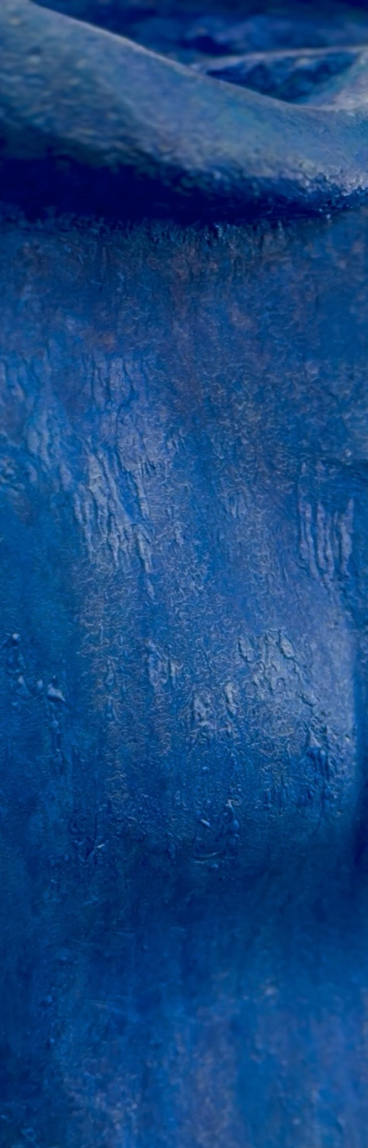 Close-up view of blue textured fabric with visible wrinkles and folds.