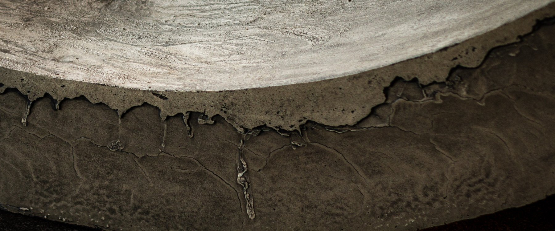 Close-up detail of a vertical concrete artifact by The Concrete Anomaly showing fractured mineral texture, layered surface variation, and eroded edge formation.