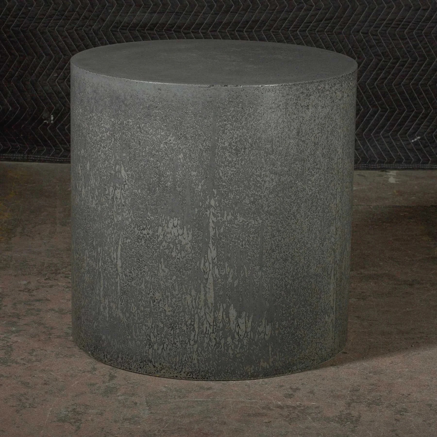 Minimal sculptural concrete furniture object with weathered charcoal finish and flowing mineral erosion patterns within line ZERO series.