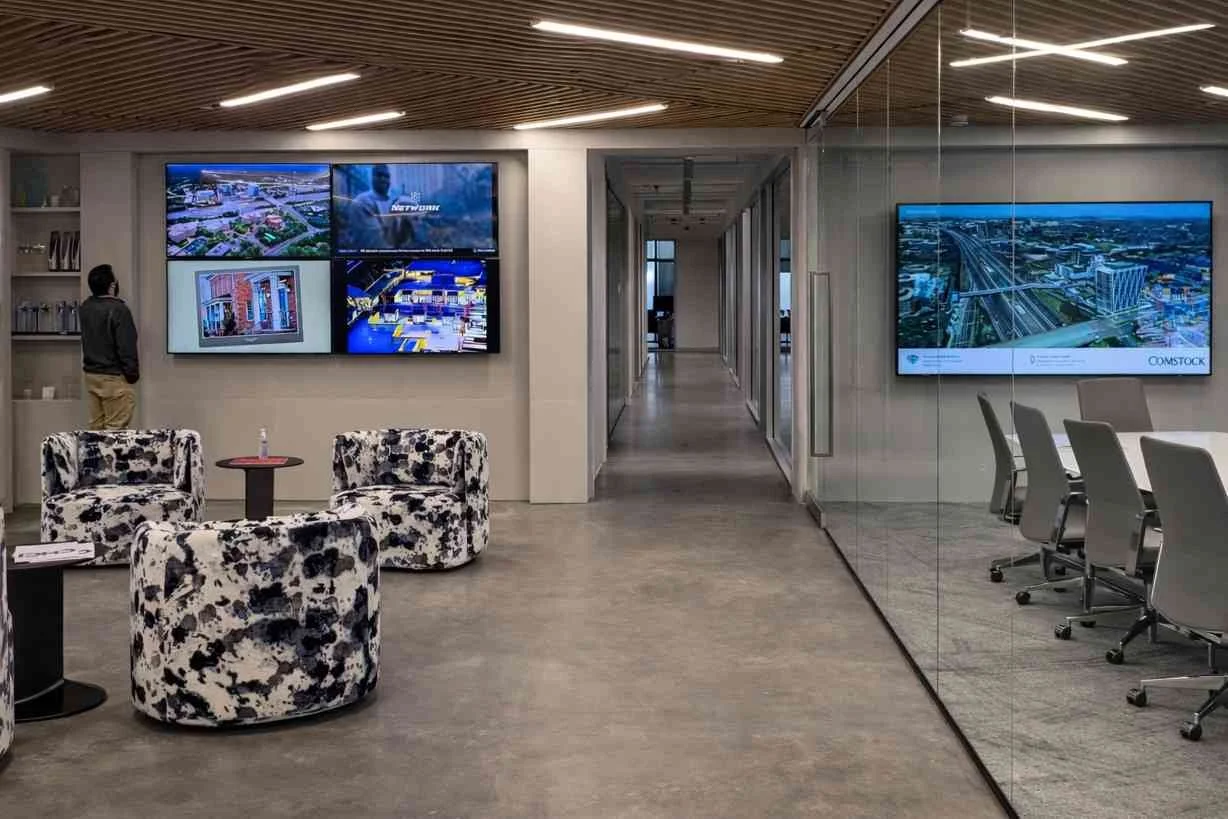 Architectural concrete wall and column wraps defining circulation and lounge zones within a contemporary office interior.