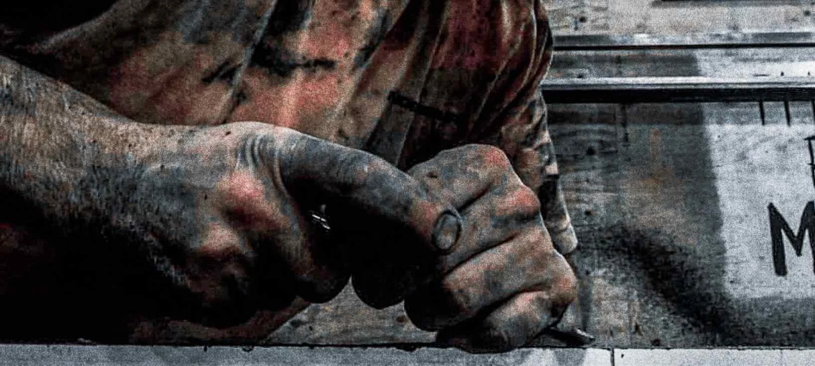 Close-up photograph of hands working concrete in a fabrication studio, showing material texture, craftsmanship, and manual construction process.