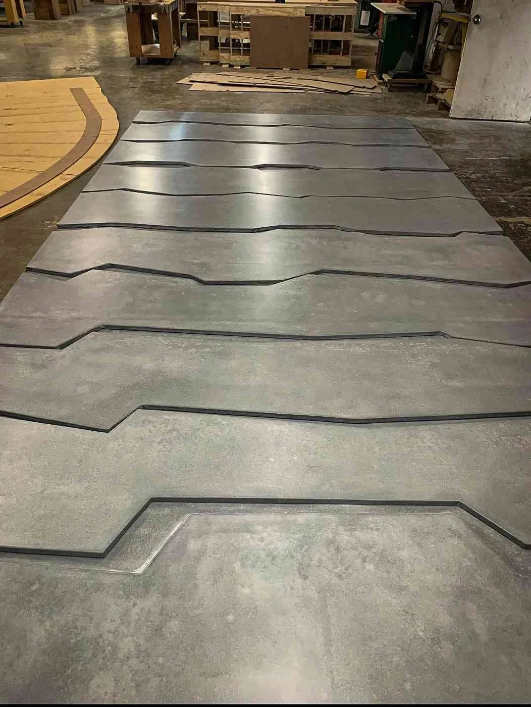 Custom cast concrete floor elements with sculpted edges staged in the workshop during fabrication.