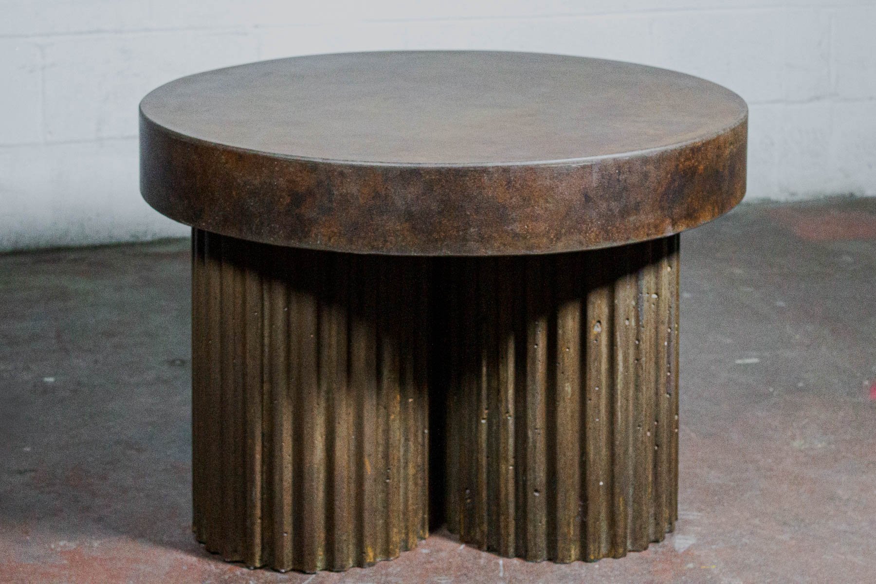 Monolithic concrete coffee table featuring rhythmic fluted geometry and a layered tobacco mineral patina by The Concrete Anomaly.