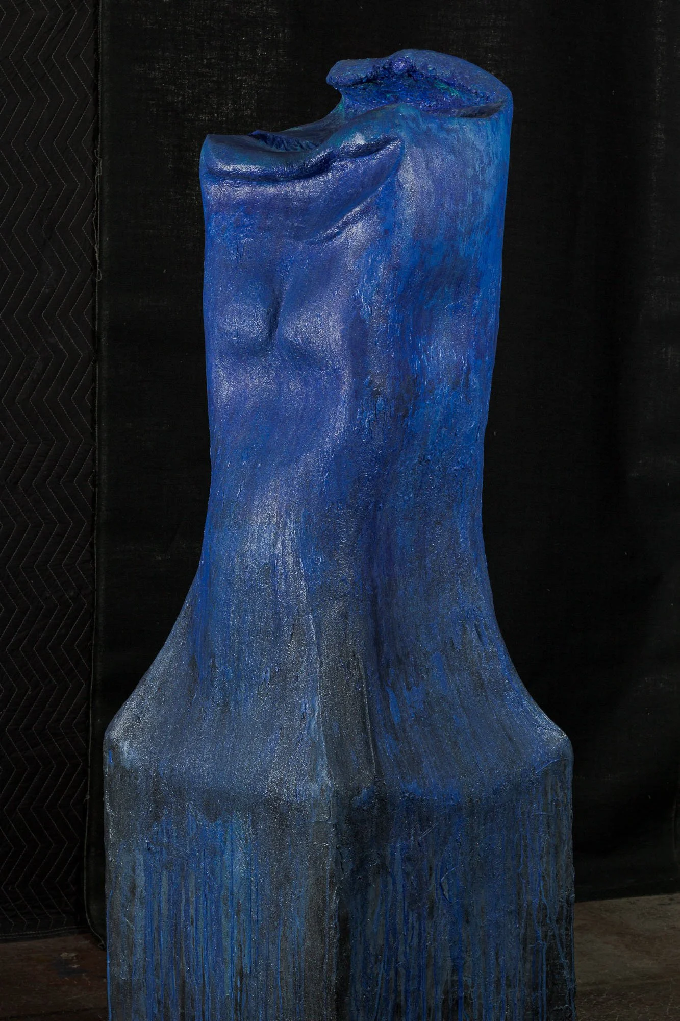 A blue textured sculpture of a human torso on a black background.