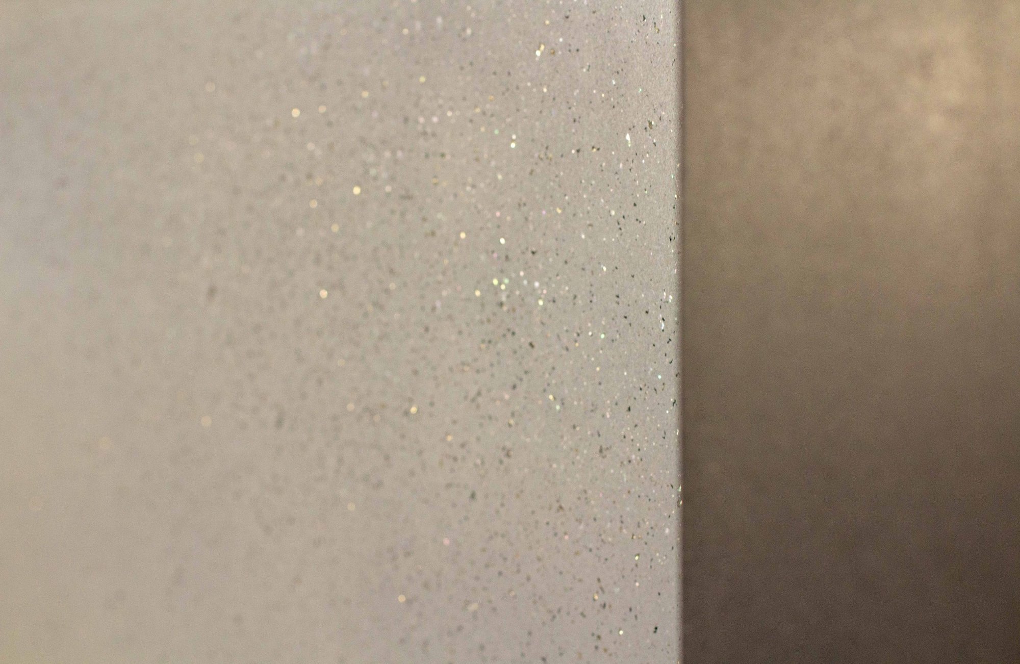 Close-up of honed salt and pepper concrete wall condition with integrated mineral refraction demonstrating light-responsive surface behavior.