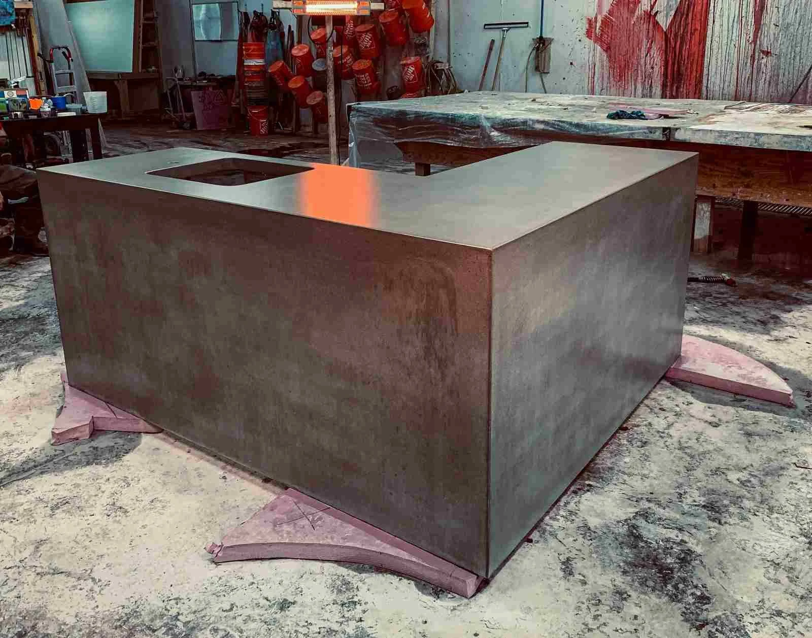Monolithic custom cast concrete kitchen island during finishing stages in the workshop.