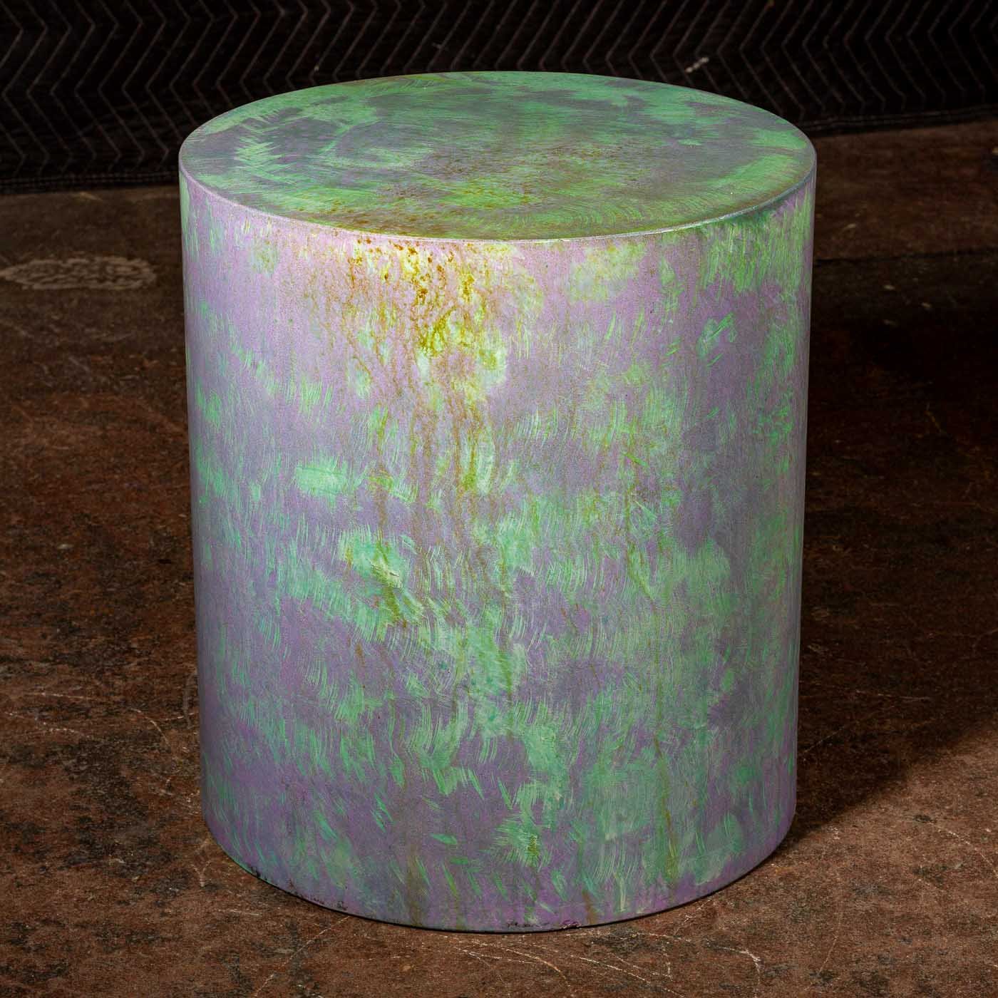 Cylindrical concrete pedestal with atmospheric violet and oxidized green patina finish photographed in studio lighting