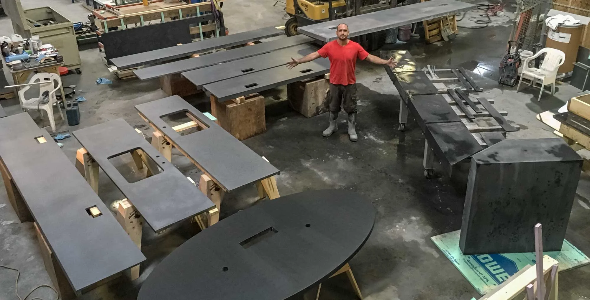 Concrete artist surrounded by custom architectural concrete pieces during an intense thirty-day experimental production period inside the workshop.