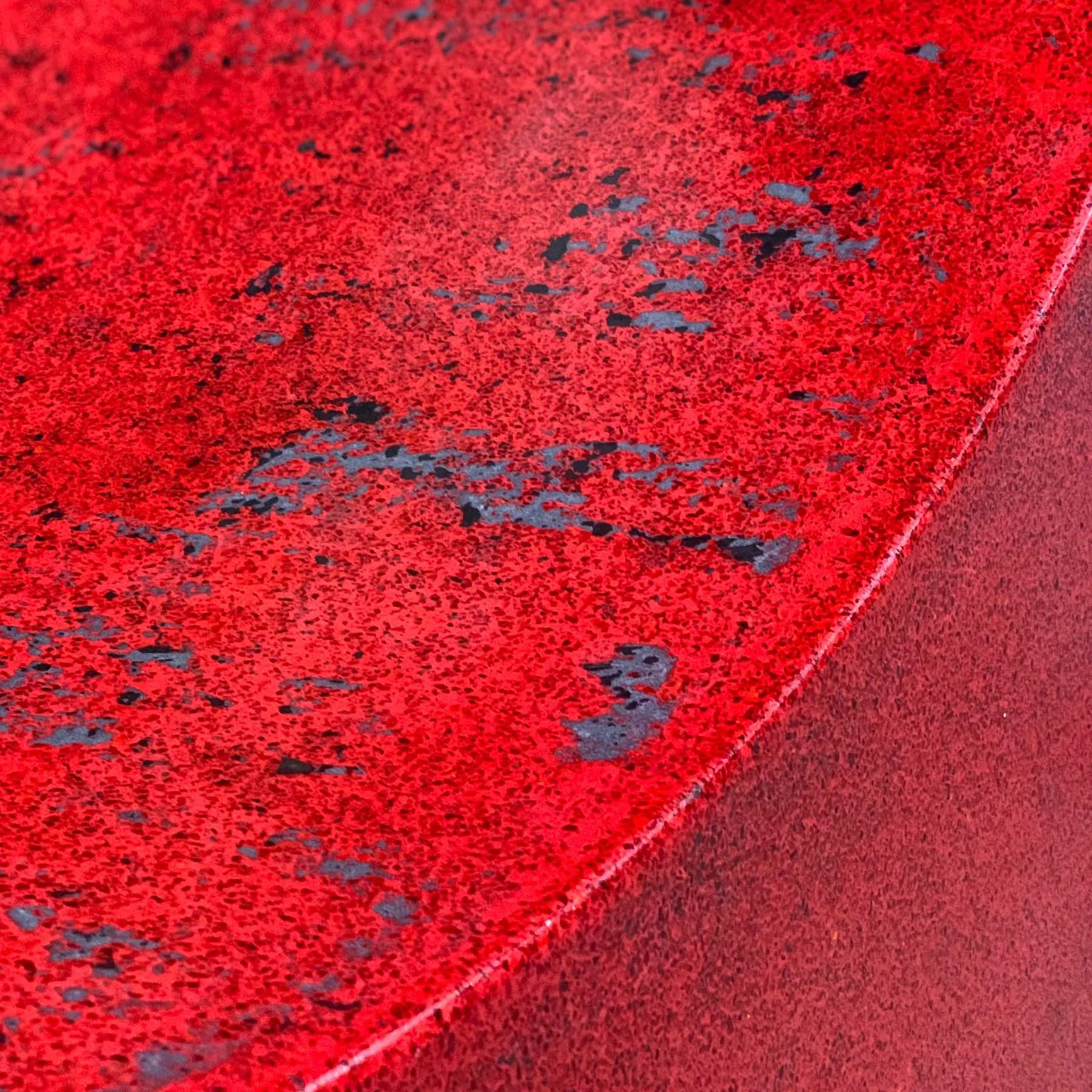 Close-up of the red terrazzo concrete surface with exposed glass and dark aggregate on the LOVE sculpture’s letter O.