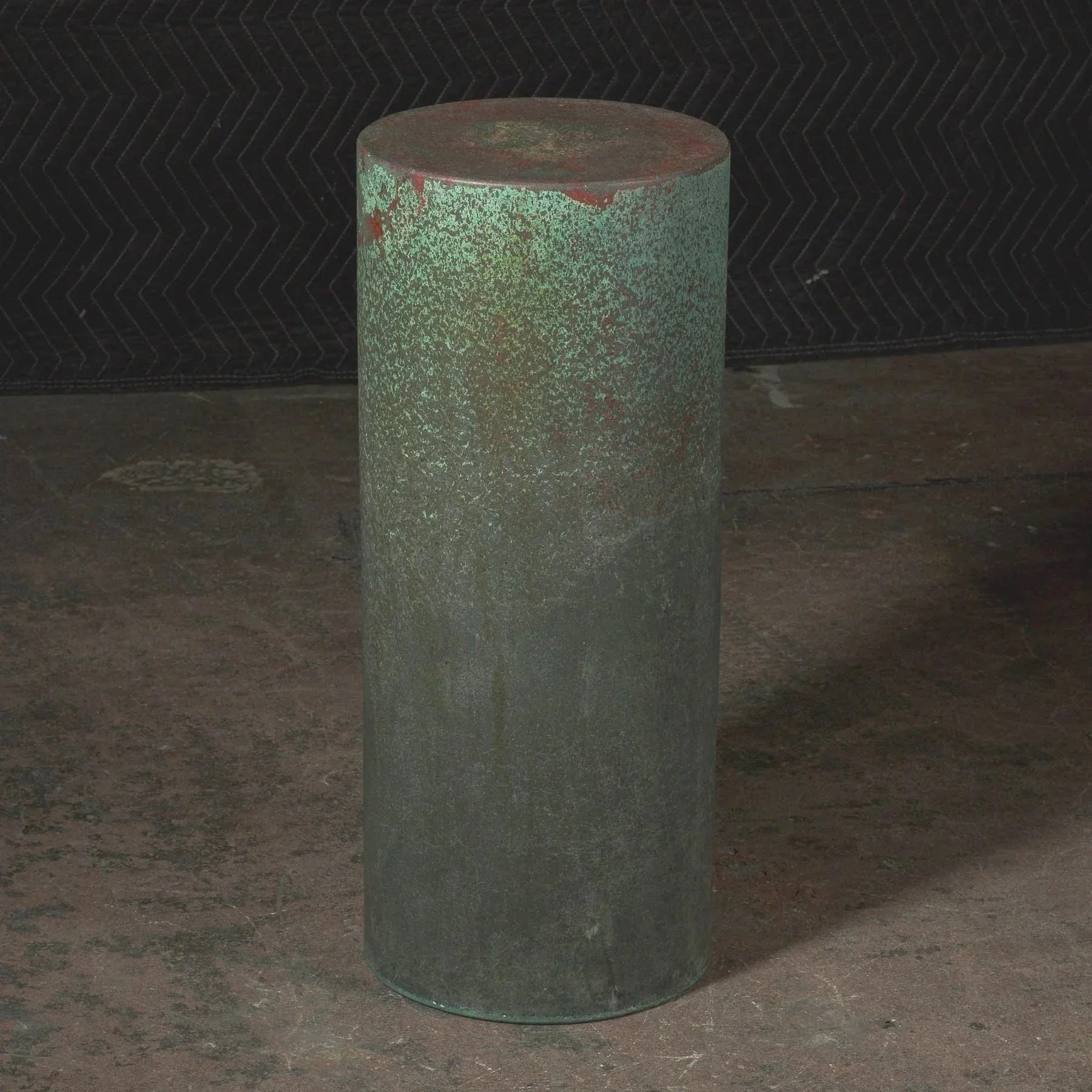 Tall sculptural concrete side table featuring monolithic form, aged metallic texture, and refined oxidized patina movement.