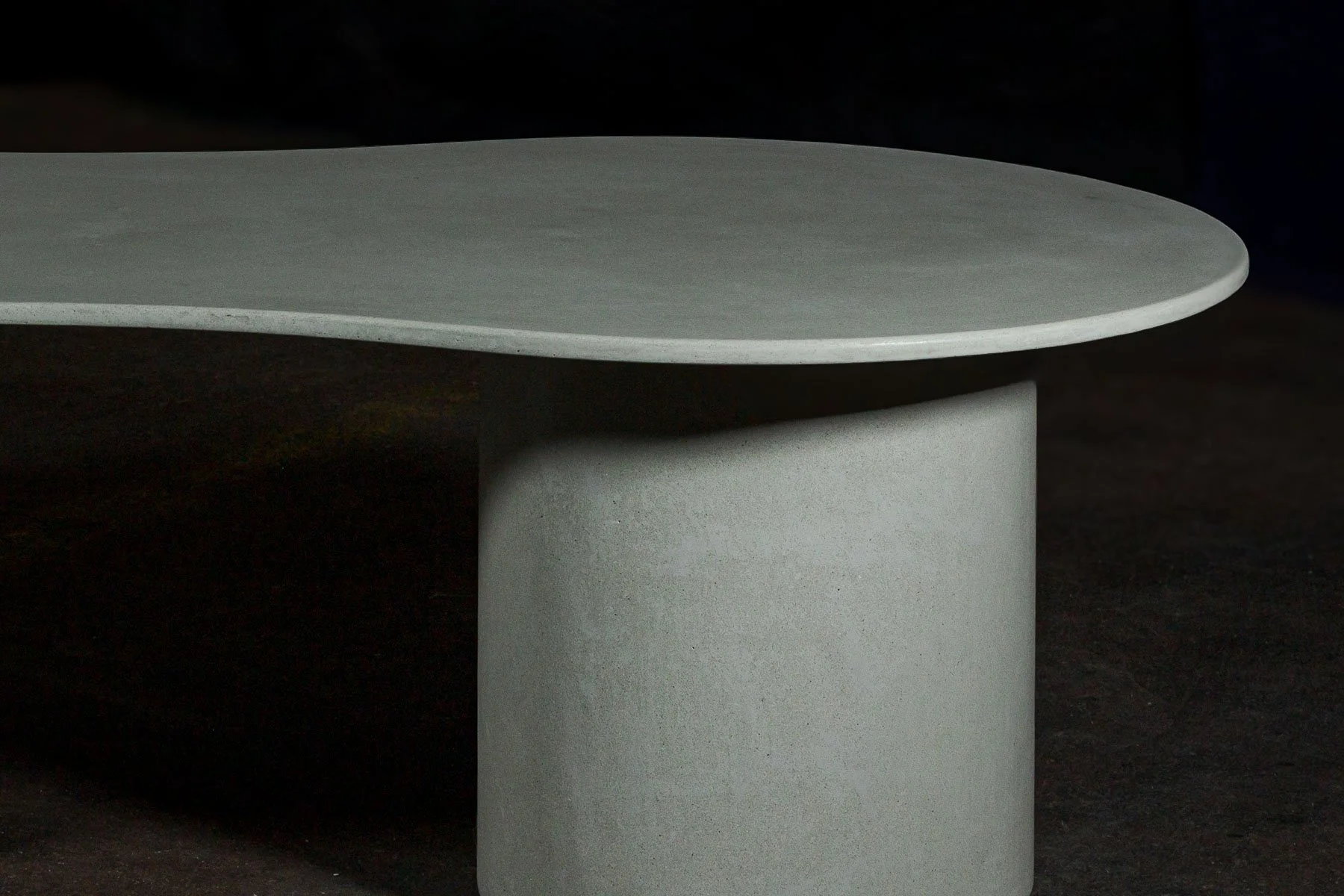 A detail focused on the visual suspension of the monolithic surface as it extends across the cylindrical pedestal supports with restrained structural presence.