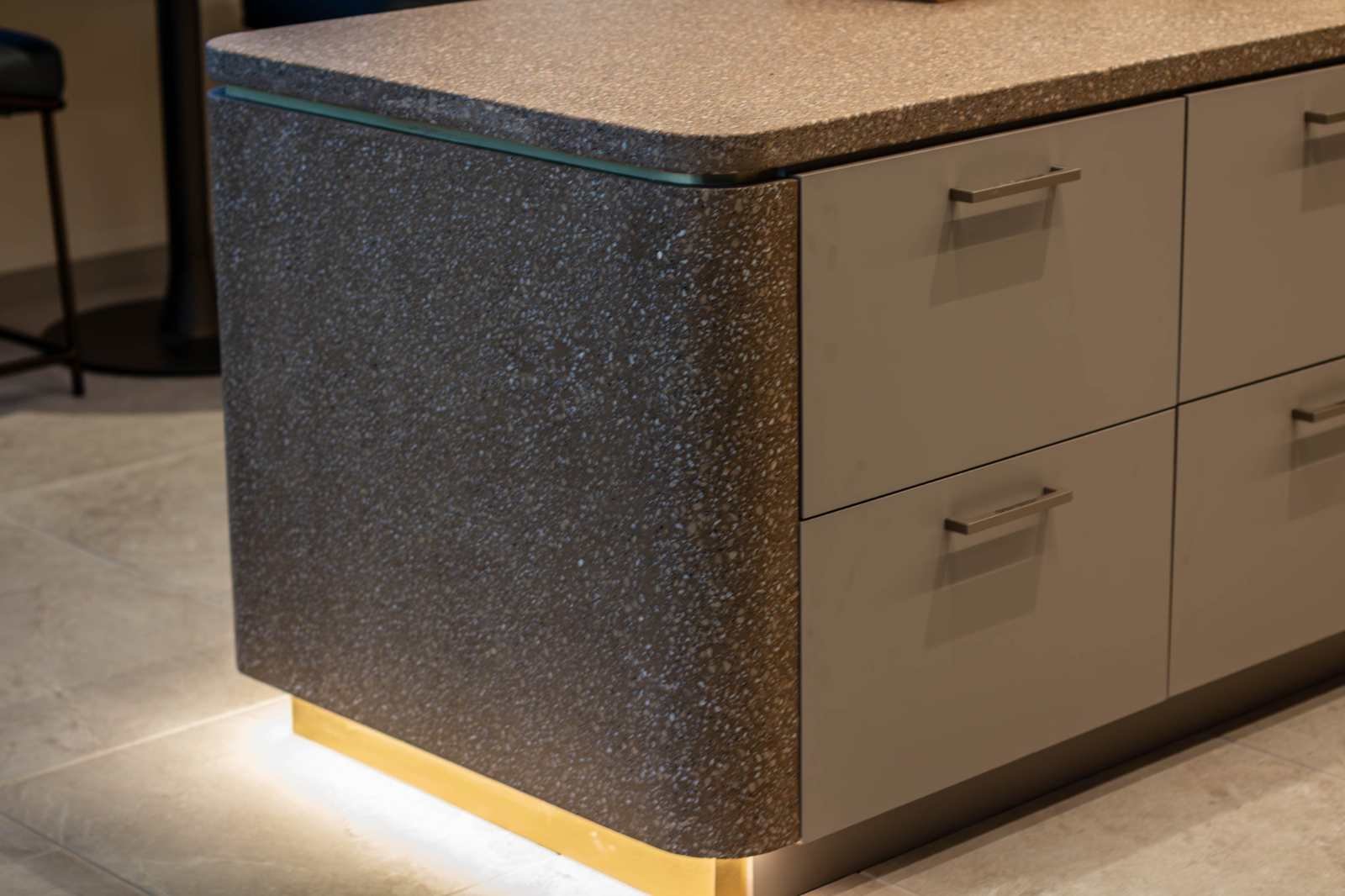Custom cast concrete kitchen island with integrated aggregate surface and illuminated base, designed as a monolithic architectural element.