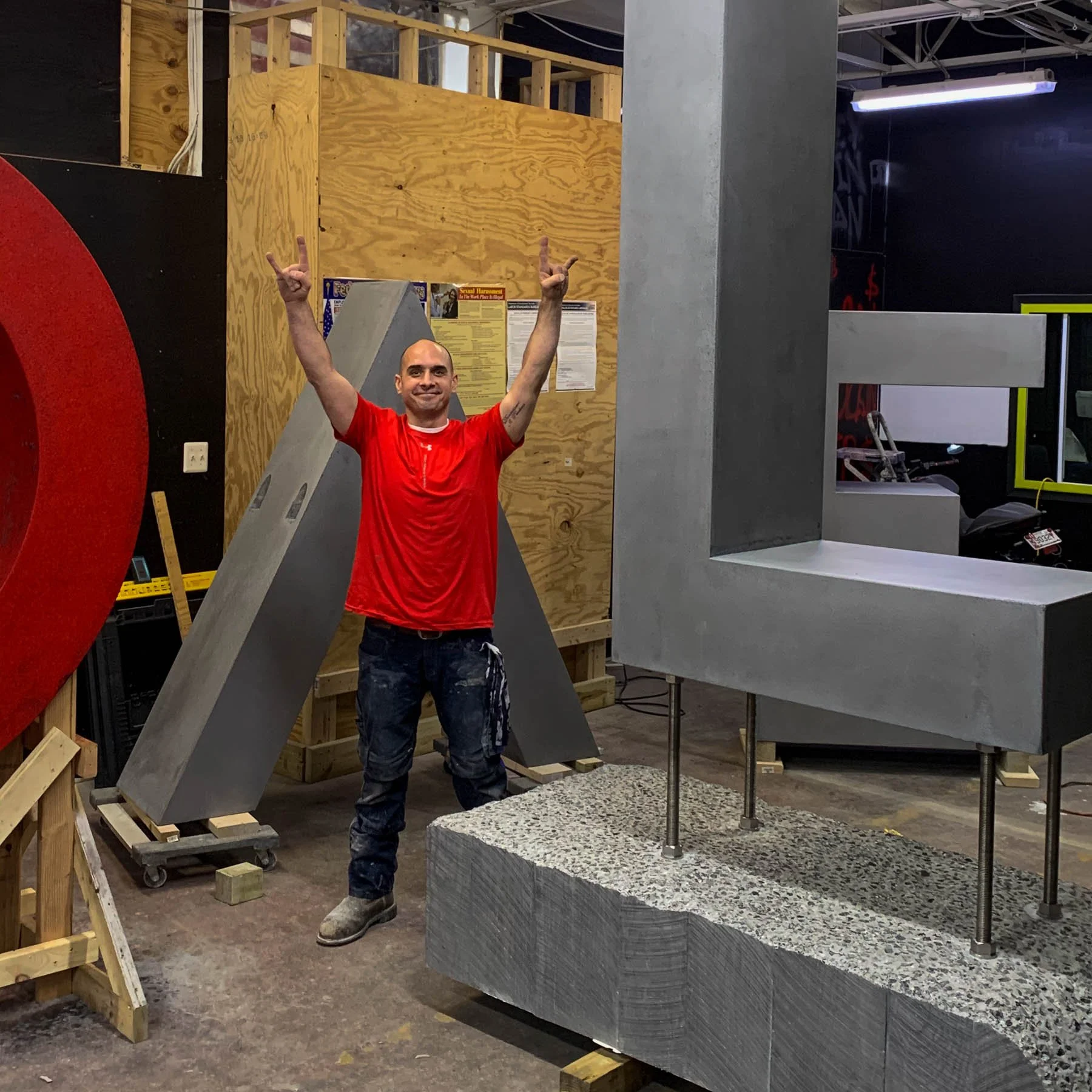 Dylan Myers standing among the monumental concrete LOVE components during studio fabrication.