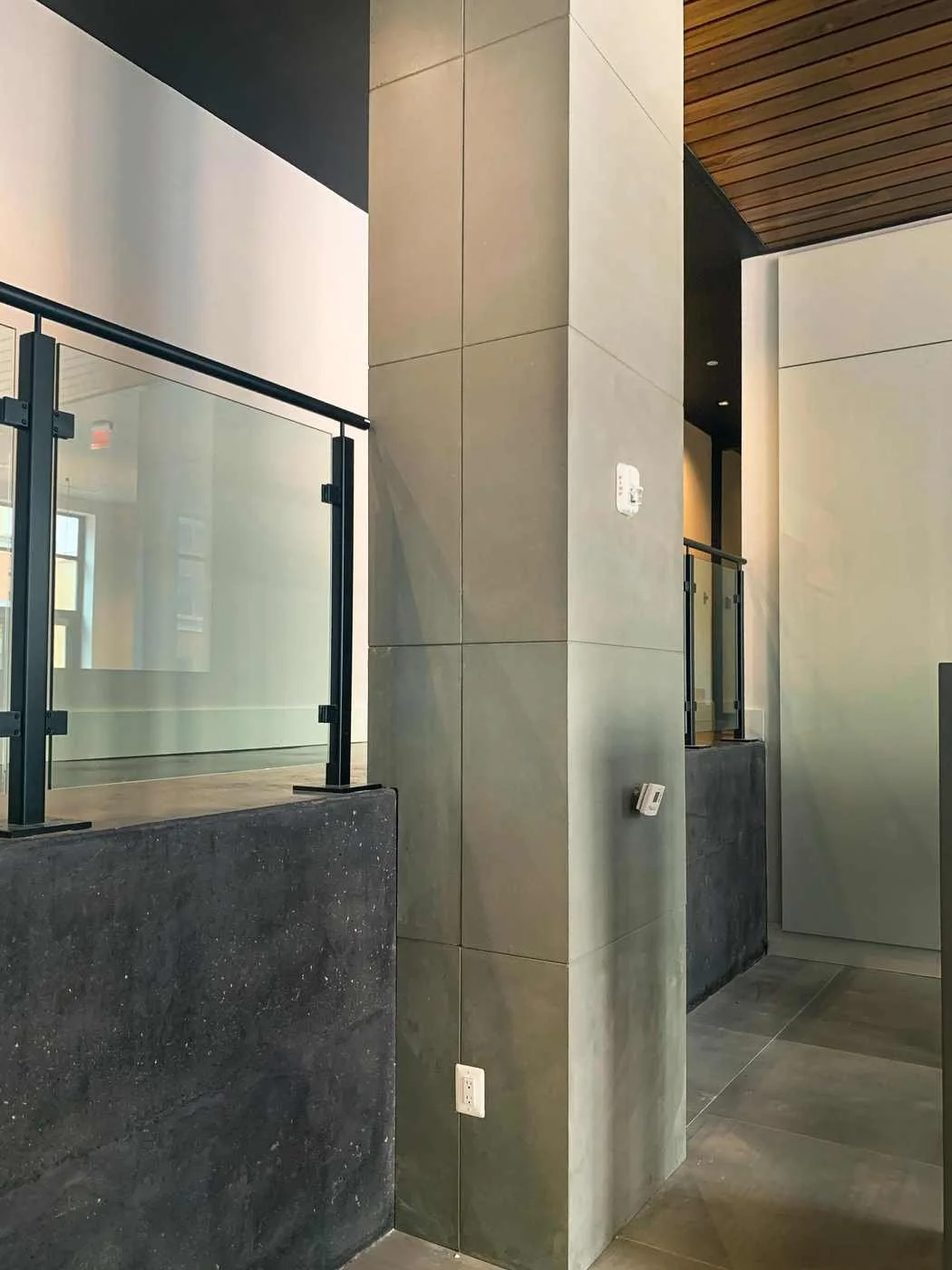 Custom cast concrete wall and column wraps integrated with glass railing in a modern architectural interior.