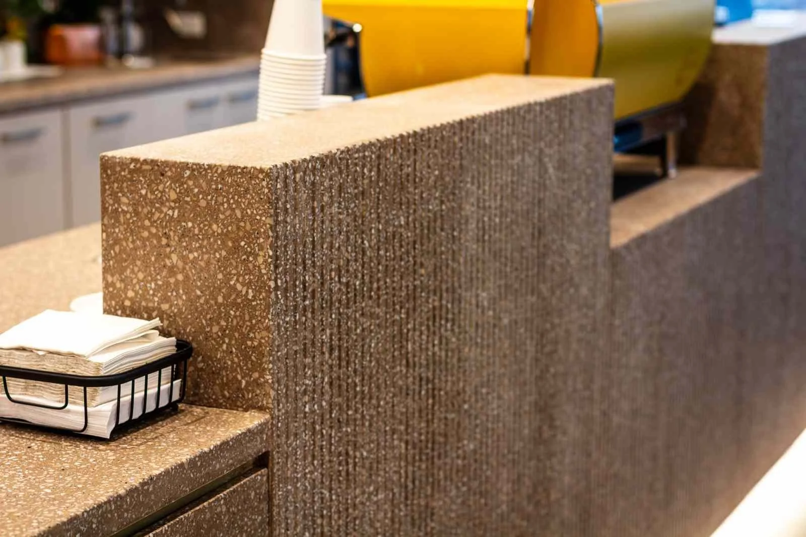 Custom cast concrete reception desk with exposed aggregate finish, shown within an active commercial interior.