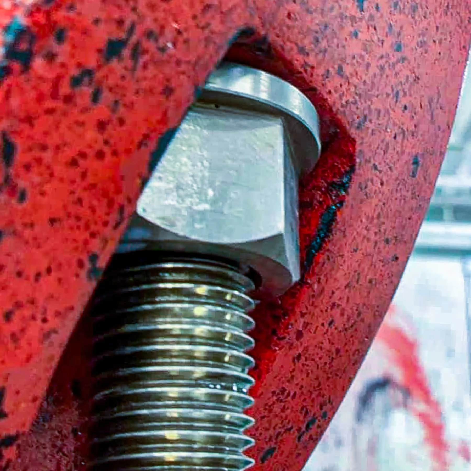 Close-up of threaded stainless-steel mounting hardware recessed into the red concrete letter O of the LOVE sculpture.