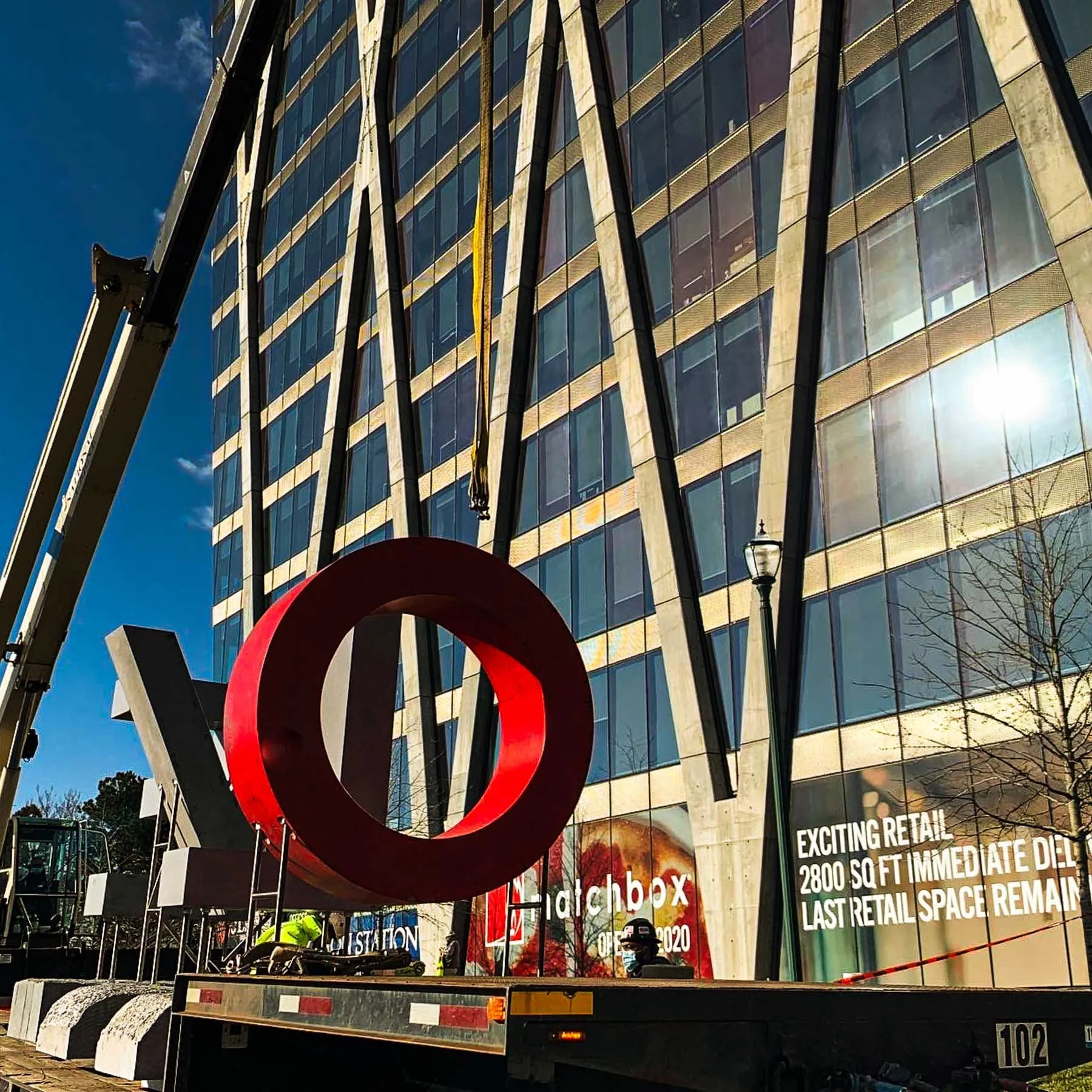 Red concrete letter O arriving by flatbed truck at Reston Station for installation of the monumental LOVE sculpture.