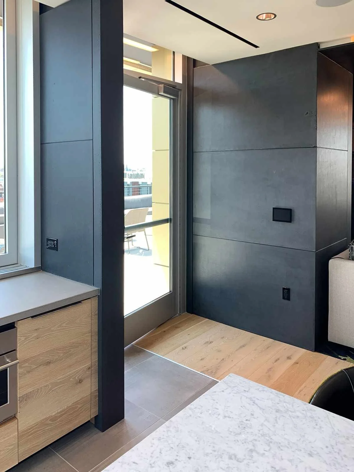 Custom cast concrete wall and countertop elements installed within a modern residential interior near a glazed opening.