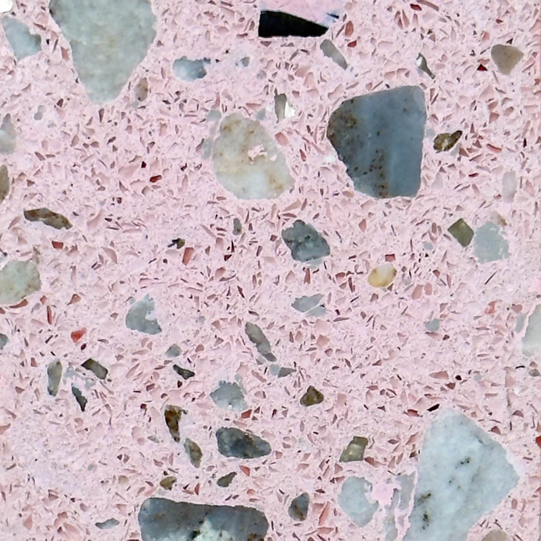 Close-up of pink terrazzo concrete featuring multicolored exposed aggregate and integrated mineral fragments by The Concrete Anomaly.