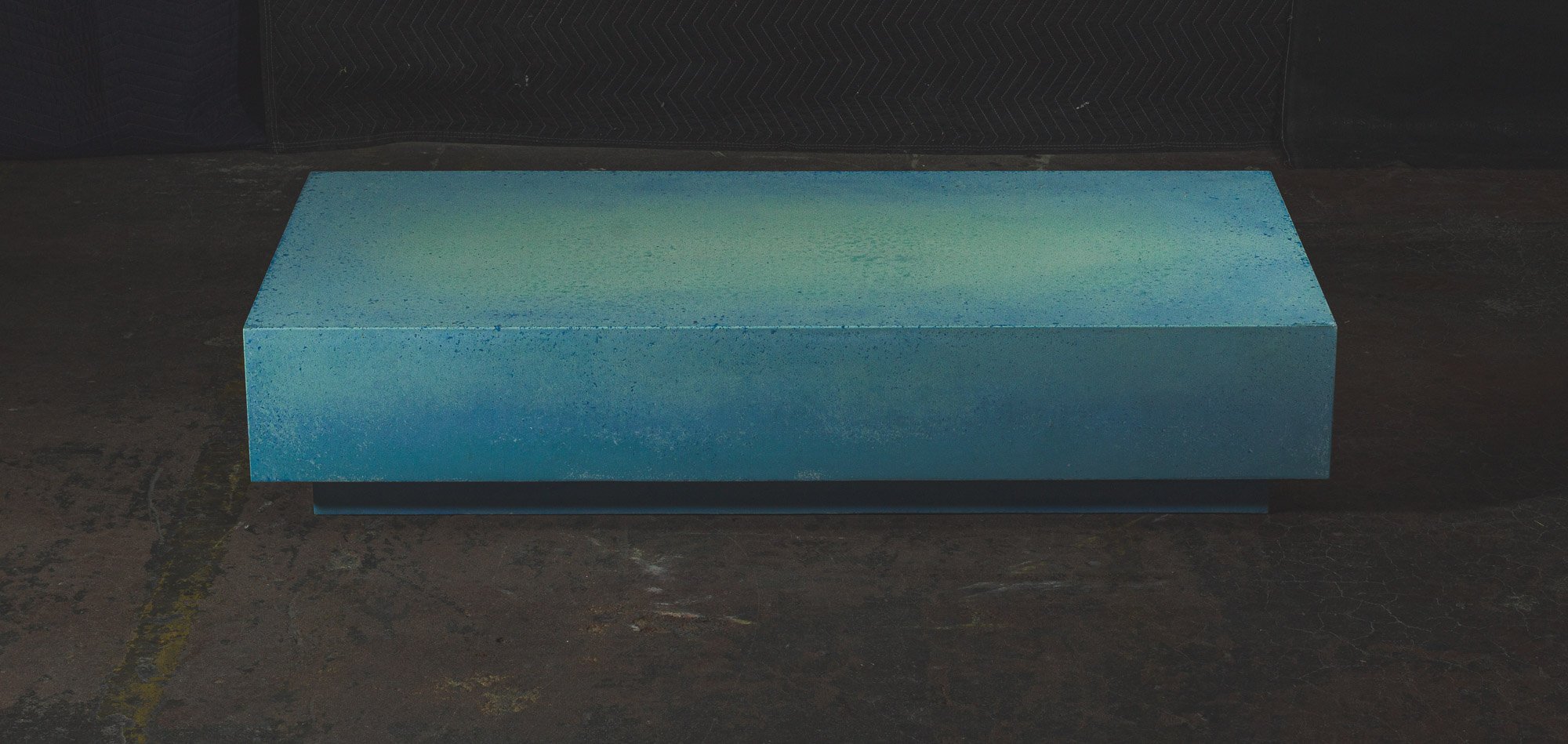Monolithic concrete coffee table with turquoise-blue pigment and minimalist rectangular form by The Concrete Anomaly.