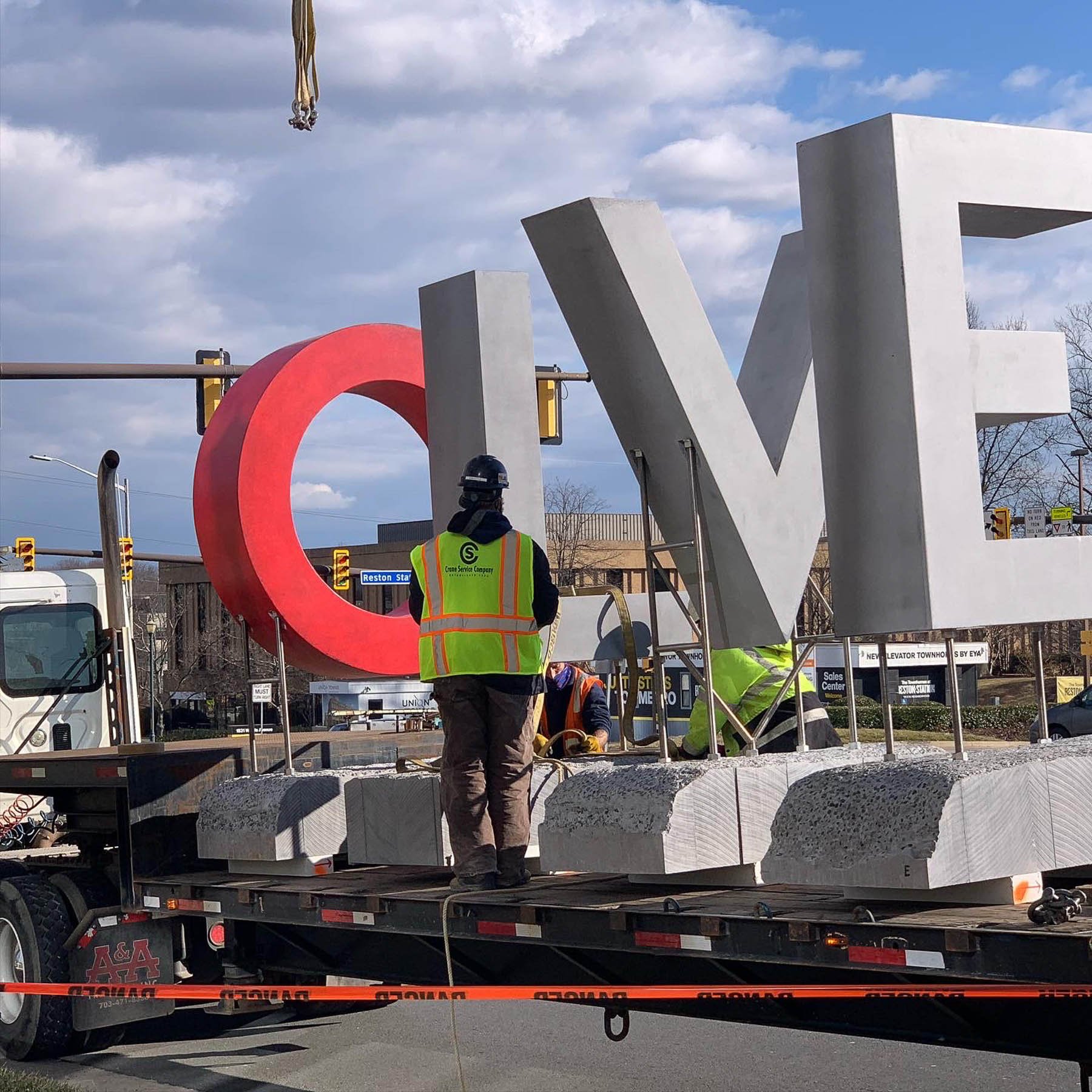 Installation crew assembling the monumental concrete LOVE sculpture at Love Park at Reston Station.